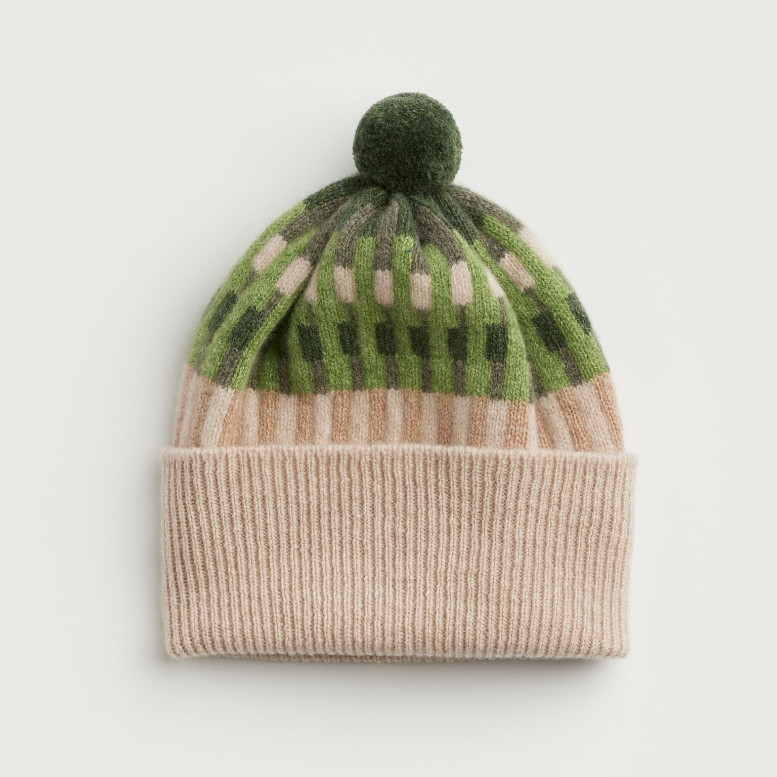 Knitted beanie with green patterned top and beige band on a light gray background