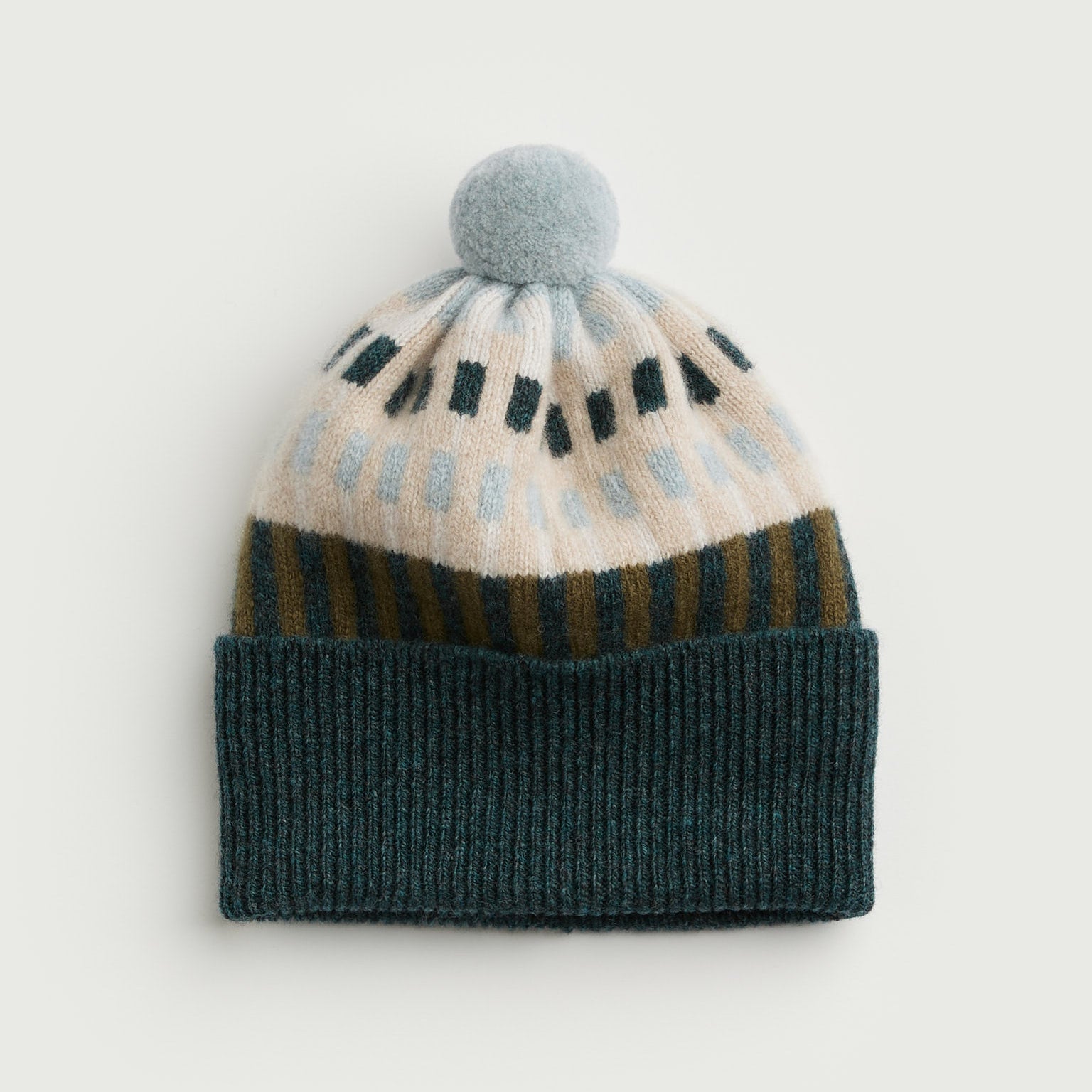 Knitted beanie with patterned design and pom-pom on a light gray background