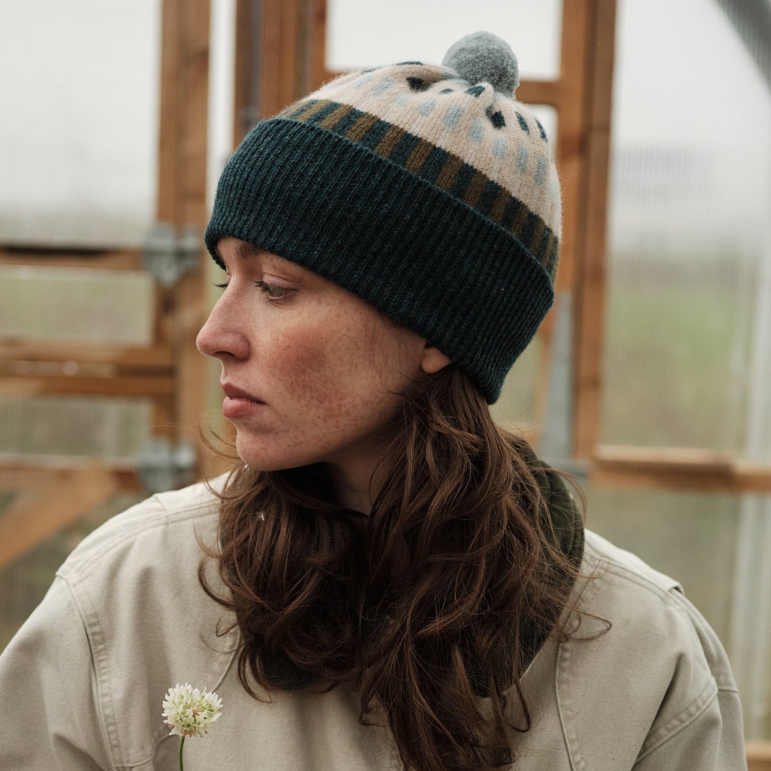Person wearing a knitted hat with a pom-pom indoors