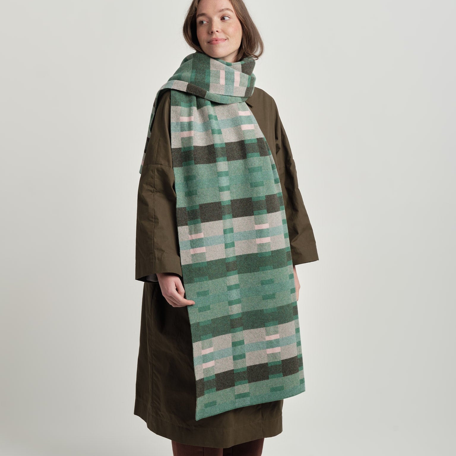 Person wearing a long green plaid scarf on a white background
