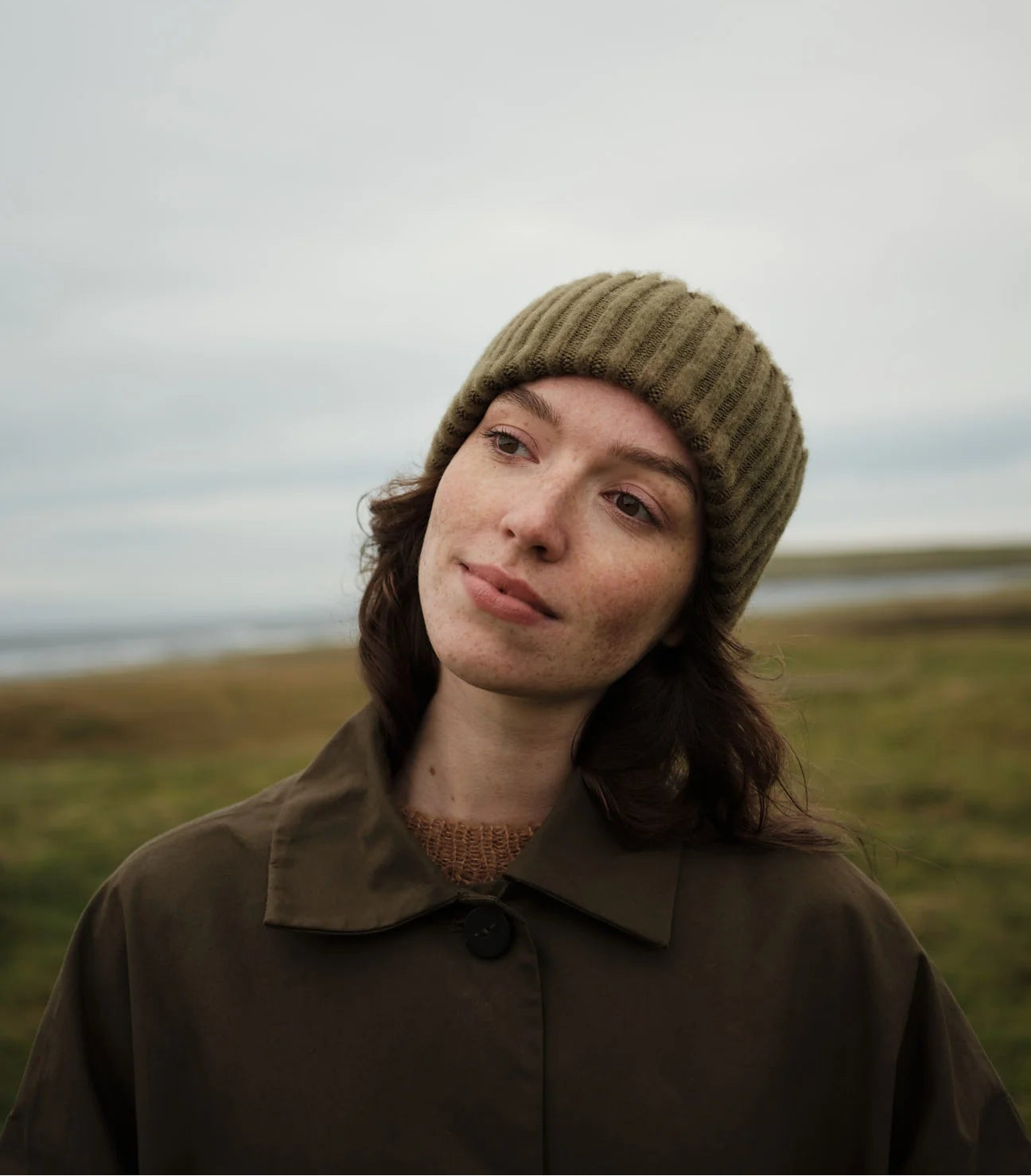 Person wearing a knit hat and coat in a natural setting