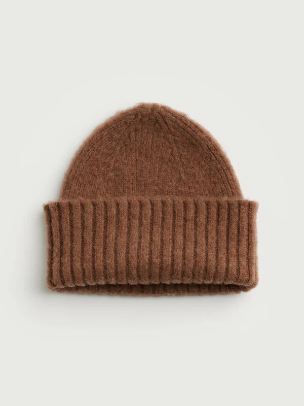 Brown knit beanie on a light beige background