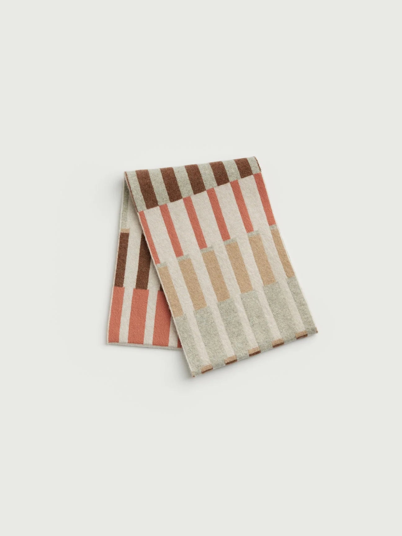 A folded striped knit scarf in a warm neutral palette of terracotta, brown, beige, and cream, displayed on a light gray background.