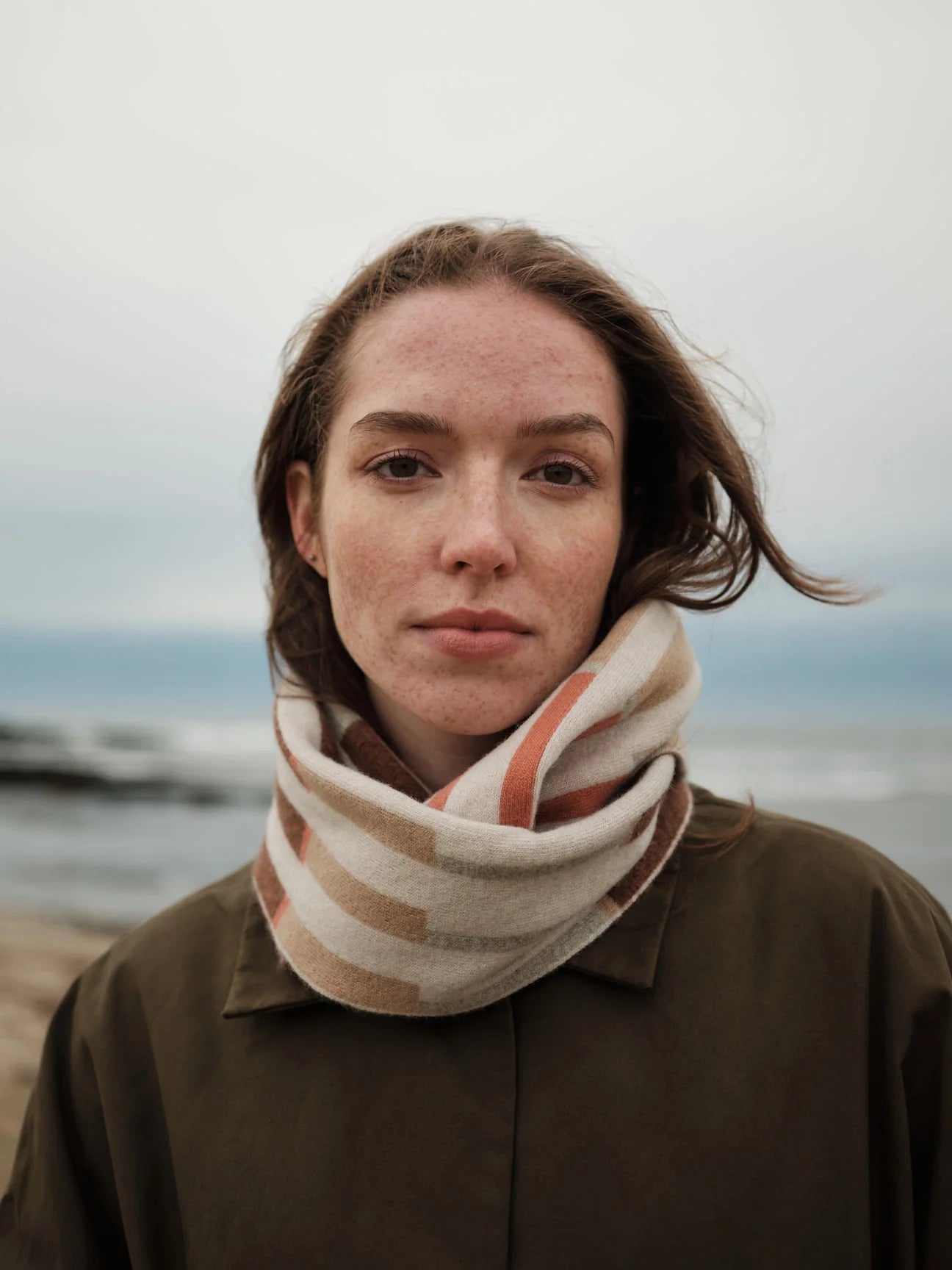 Person wearing a striped scarf with a blurred natural background