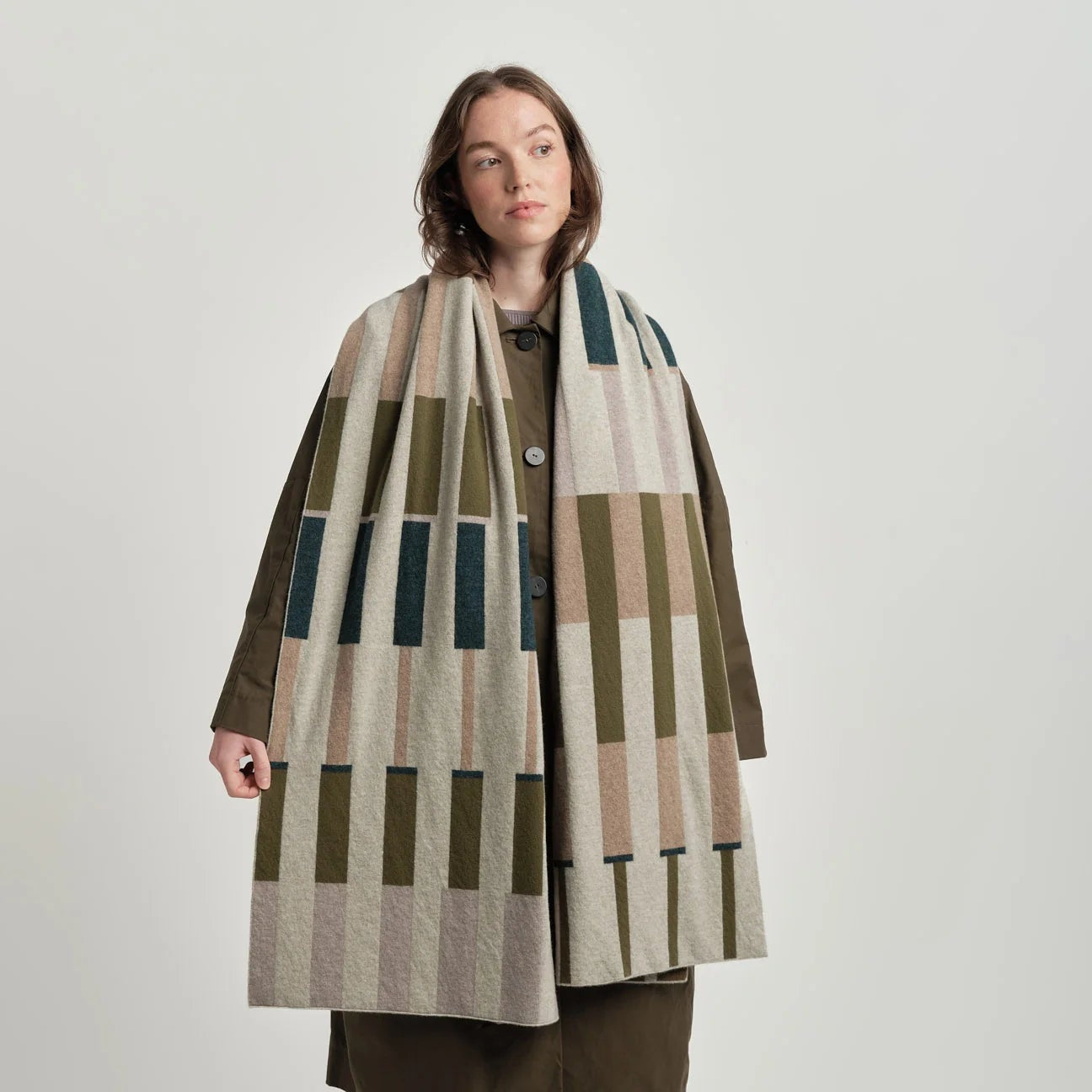 Woman wearing a patterned coat with a geometric design on a plain background