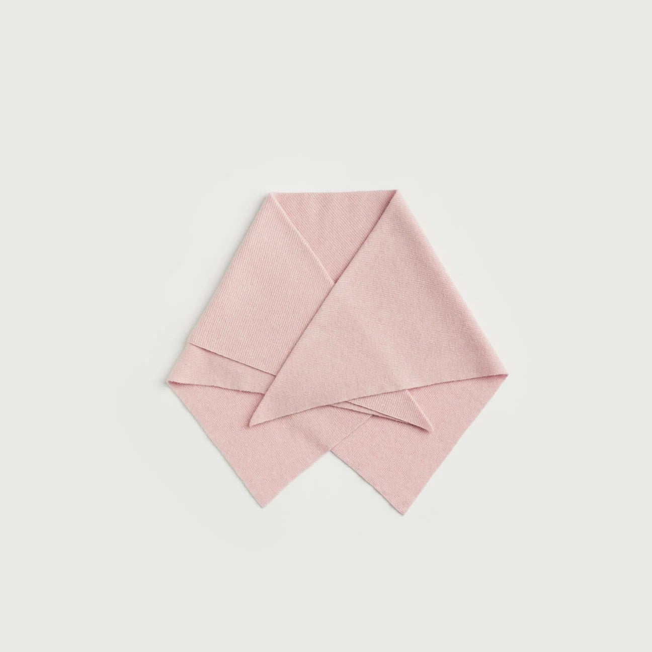 Pink fabric folded into a triangle shape on a light gray background