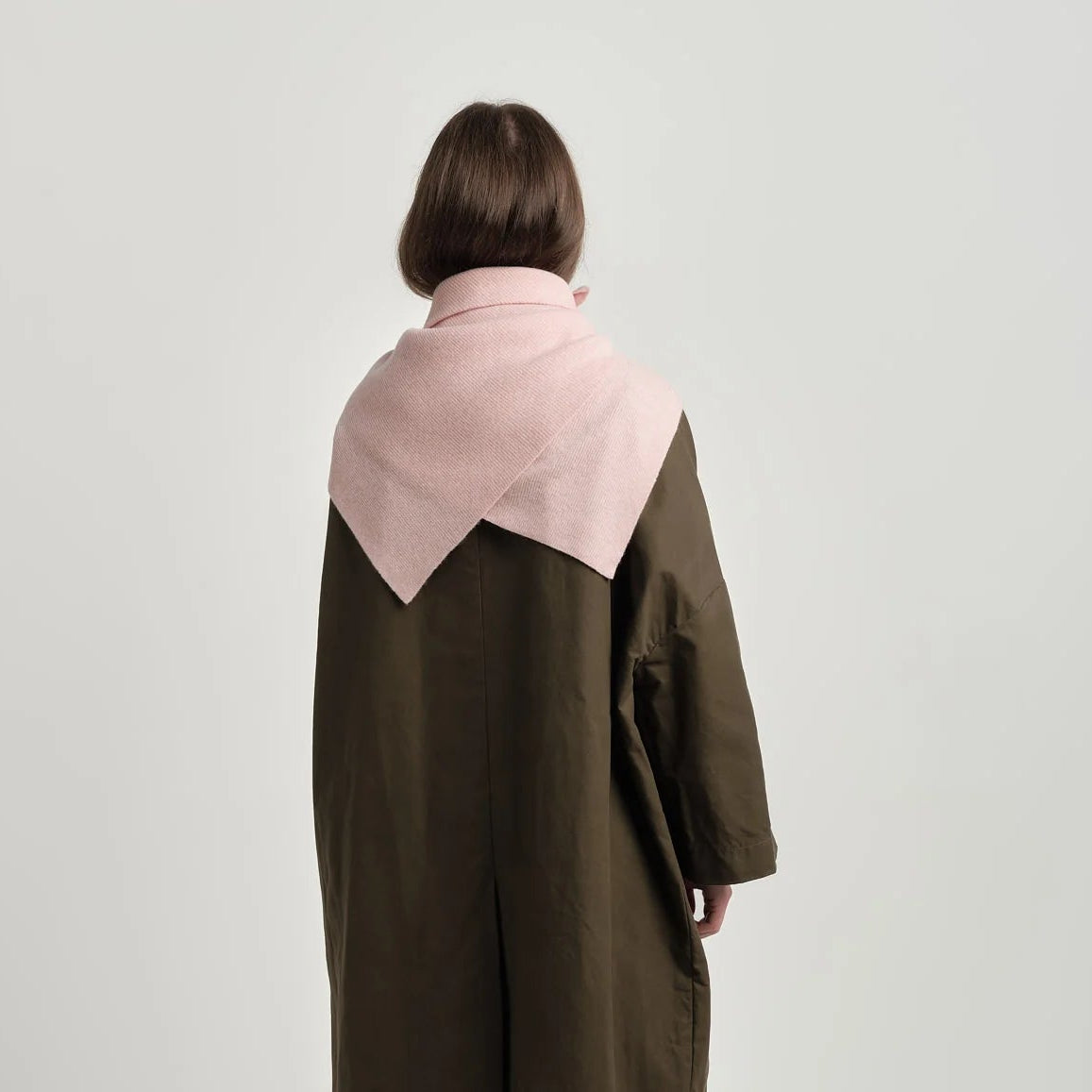 Person wearing a long coat with a pink and brown color block design on a white background