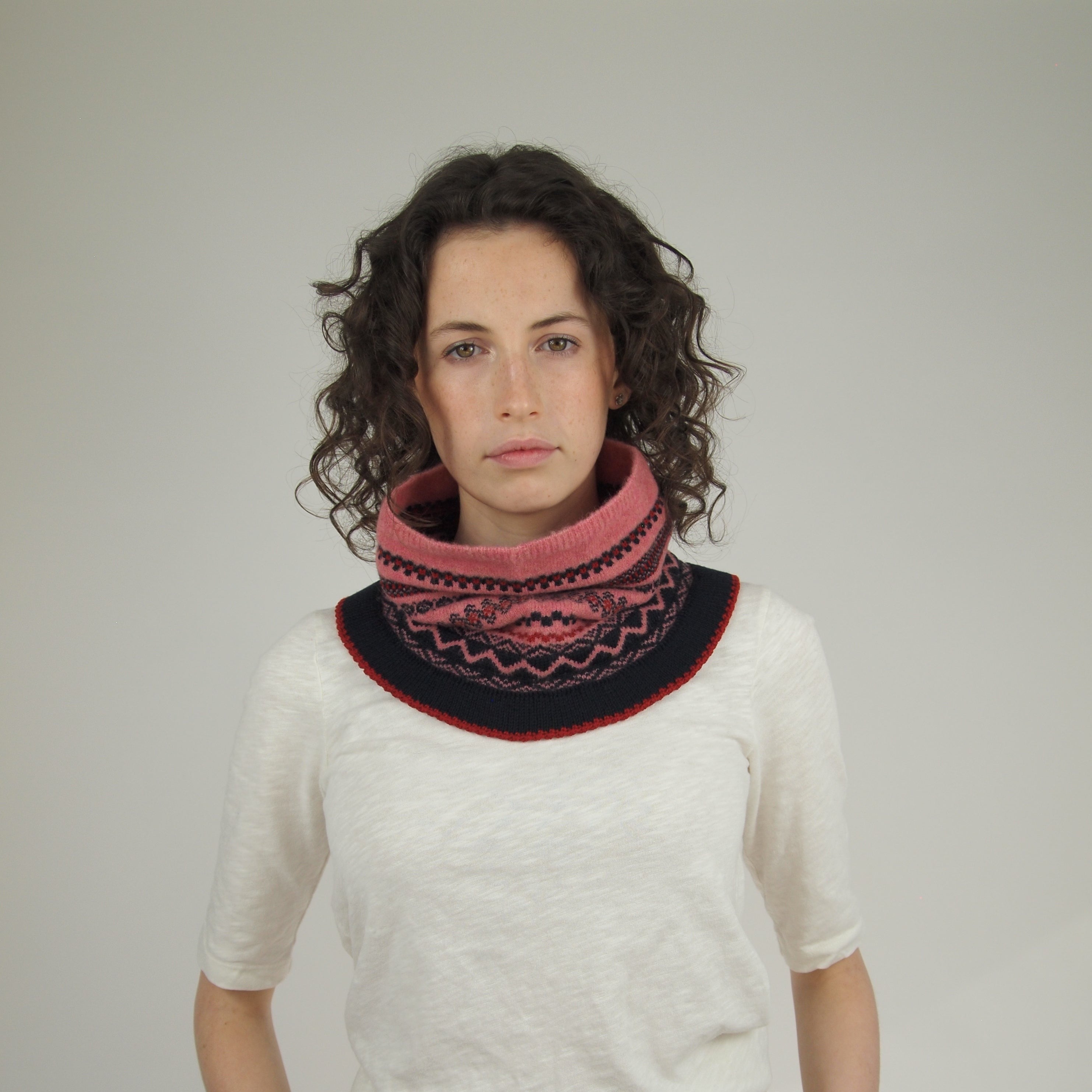 Pink and navy Fair Isle patterned knitted neck warmer.  The warmer has a ribbed edge in dark red.