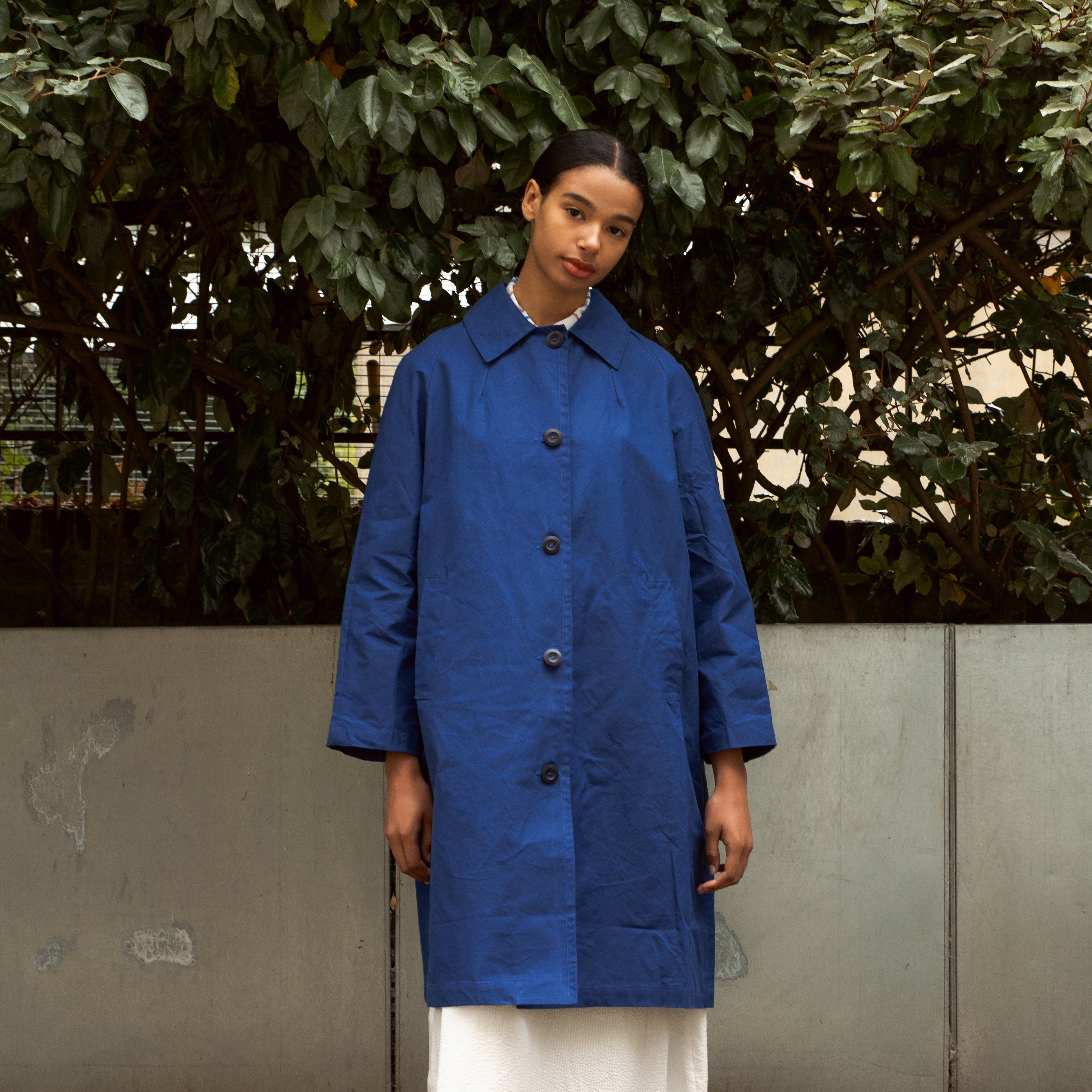 A cobalt blue, knee-length button-up coat with a collared neckline.