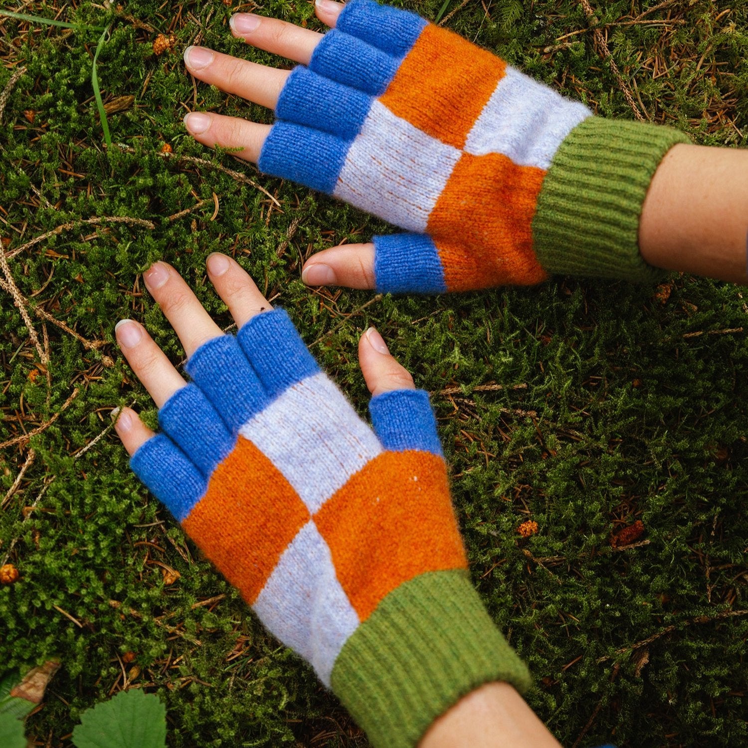 Pair of fingerless gloves in blue, orange, white, and green knit squares.