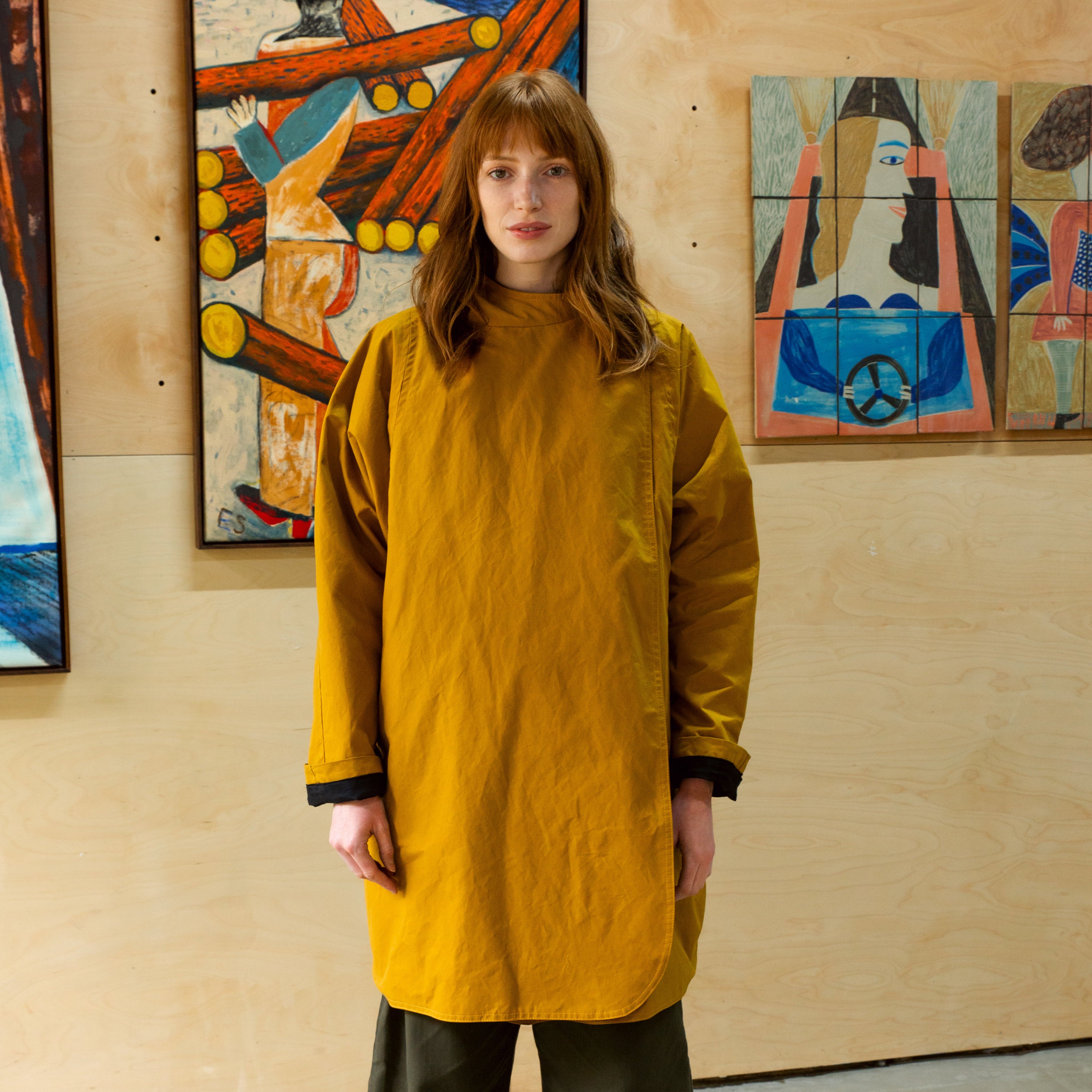 Mustard-yellow long-sleeved tunic with a high neckline and curved hemline.  The sleeves have dark cuffs.