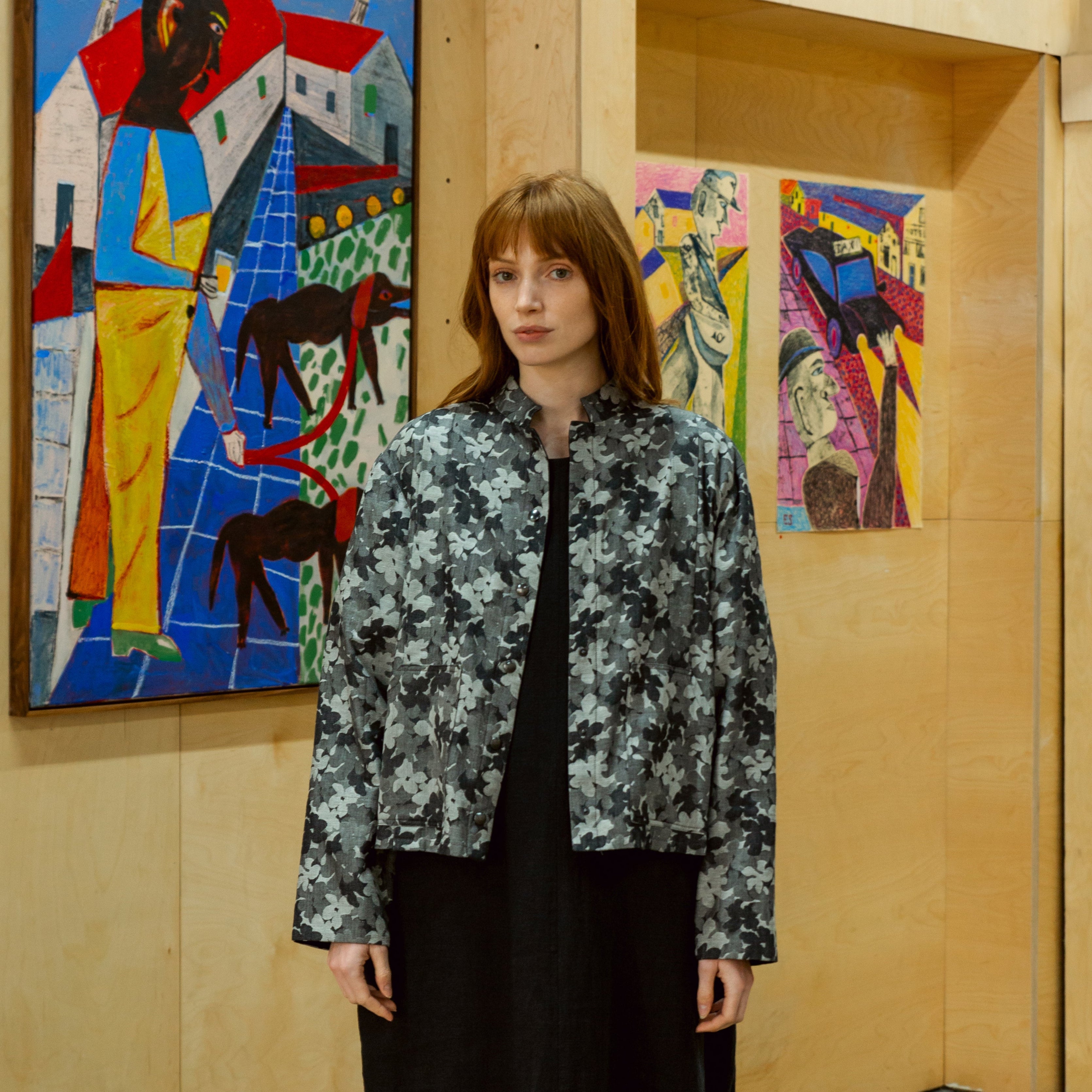 Woman wearing a gray cropped jacket with a subtle floral pattern.