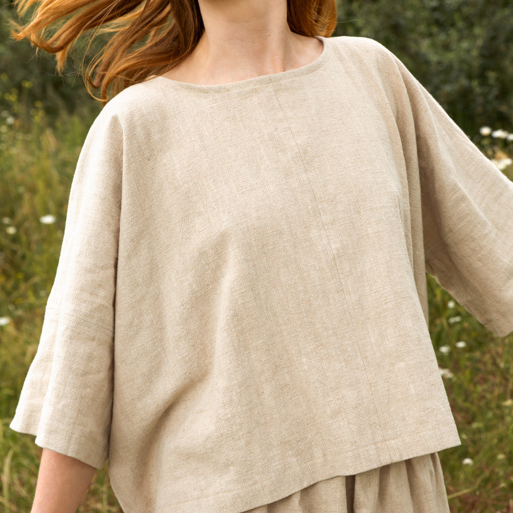 Beige linen top with a boat neck and loose, three-quarter sleeves.  The fabric has a subtle textured weave.