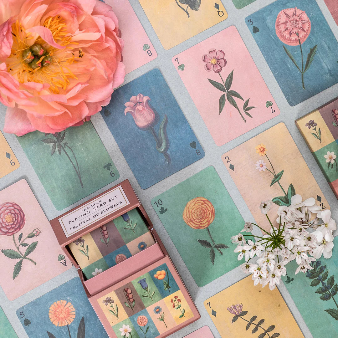 Set of playing cards with floral designs on a flat surface.