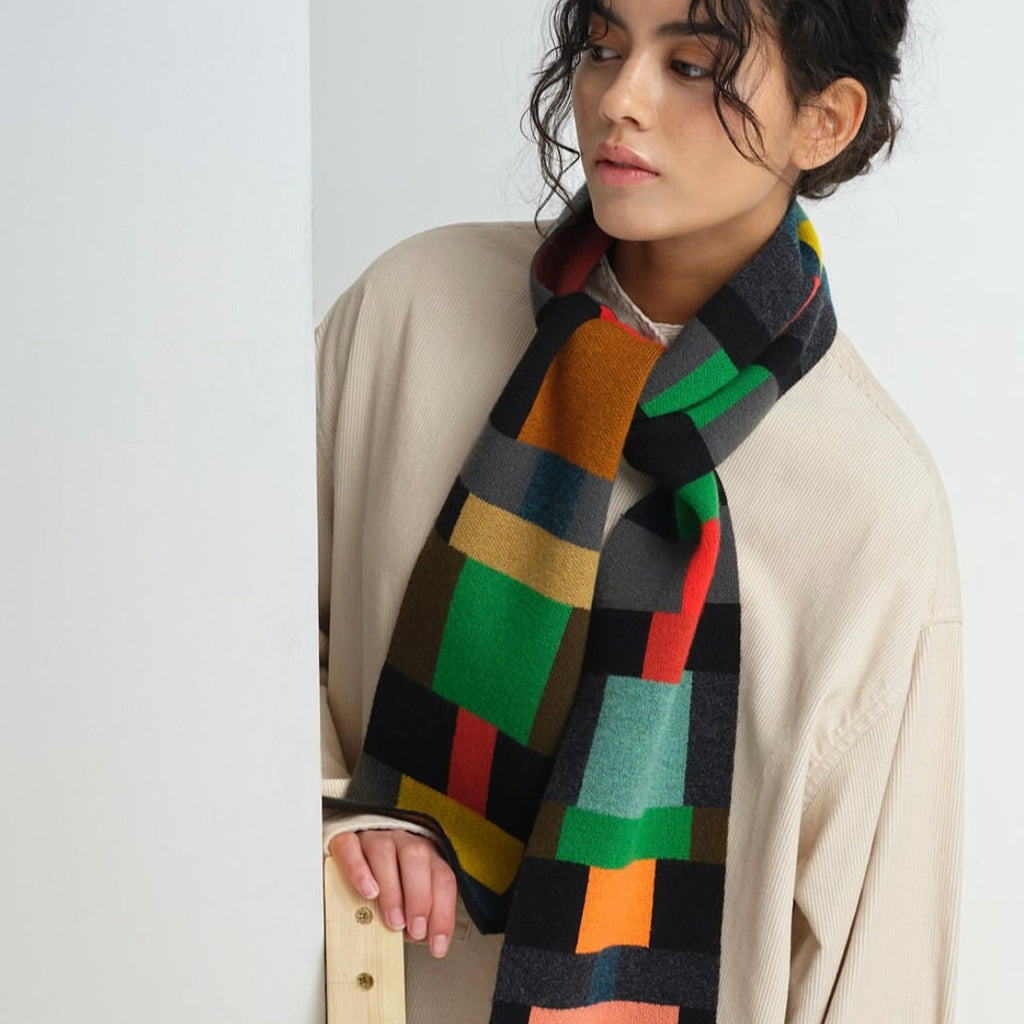 Multicolored wool scarf with a geometric block pattern in shades of green, orange, red, black, and gray.