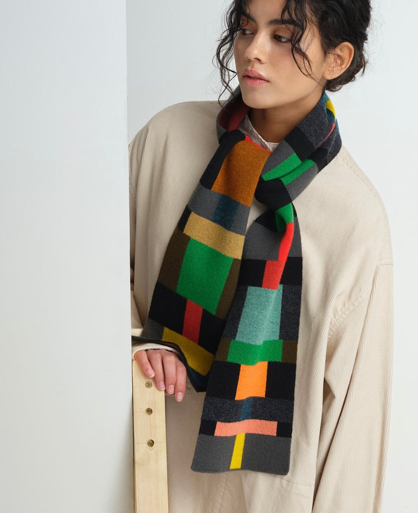 Multicolored geometric patterned wool scarf.  The scarf features blocks of green, orange, red, grey, and tan.