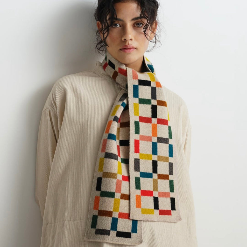 Multicolored geometric patterned wool scarf.  Off-white base with squares of red, teal, yellow, and black.