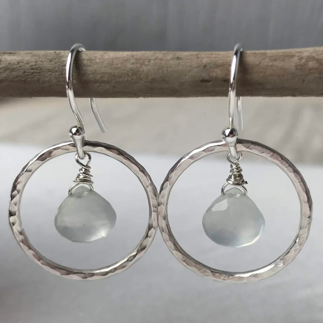 Pair of hammered silver hoop earrings, each featuring a pale grey gemstone drop.