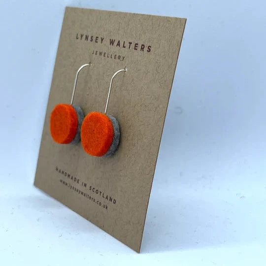 Pair of handmade felt earrings; orange and grey discs on silver hooks.