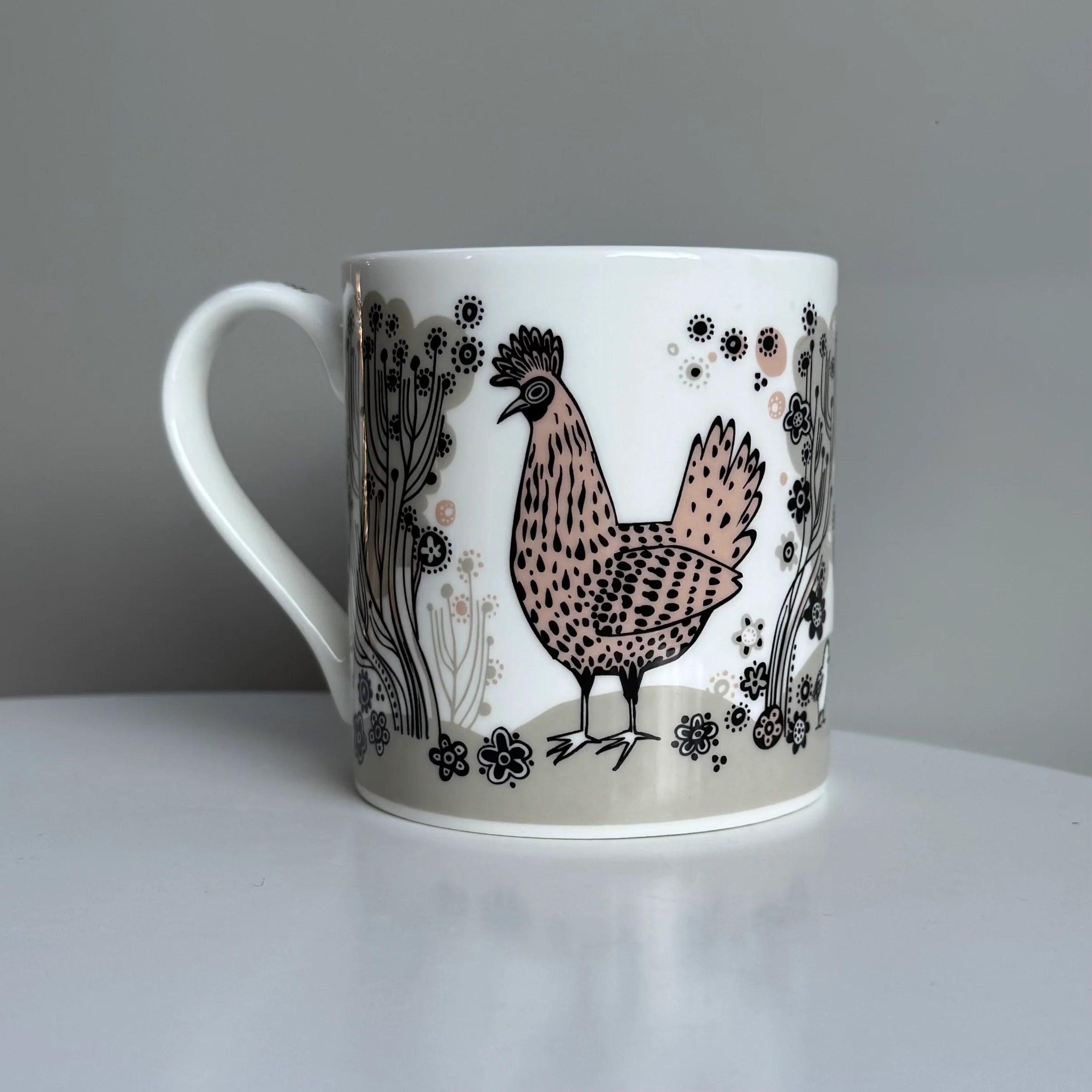 White mug with a chicken illustration on a gray background