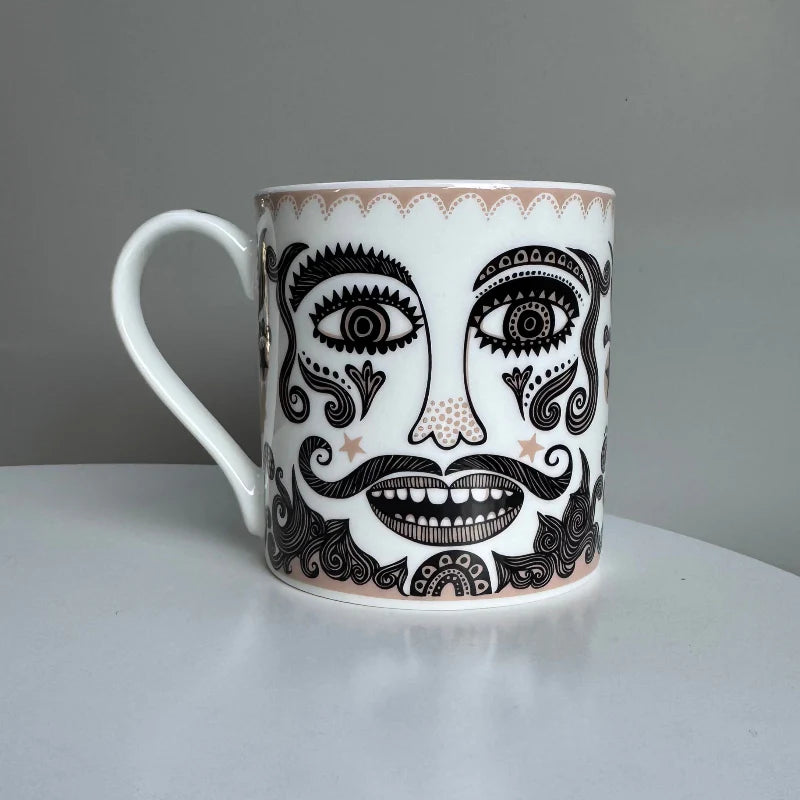 White mug with black face design on a gray background