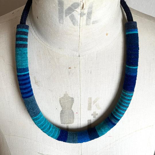 Striped fabric necklace in teal, blue, and gray hues.  The necklace is thick and forms a large, open circle.