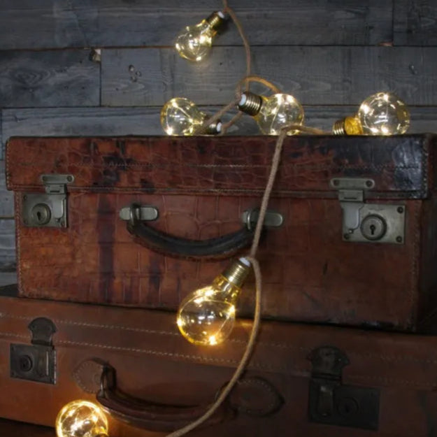 String of warm-toned Edison bulb lights draped over vintage suitcases.
