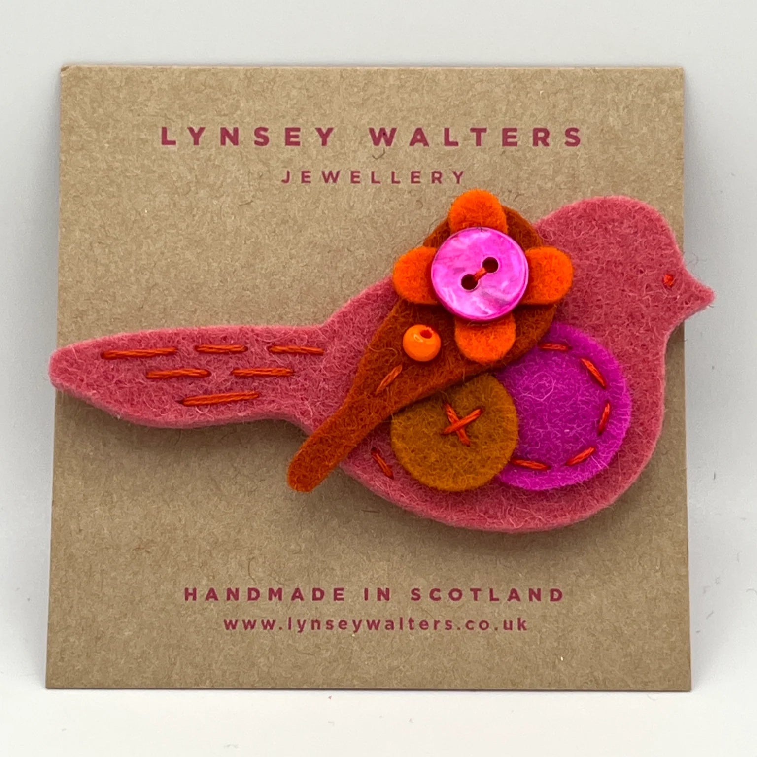 Pink felt bird brooch adorned with orange and fuchsia felt accents and buttons. Handmade in Scotland.