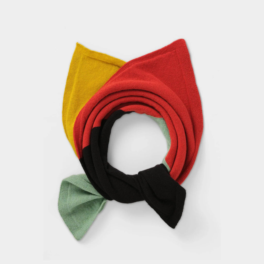 Multicolored knitted scarf in red, black, mustard yellow, and sage green. Rolled and tied in a circular shape.