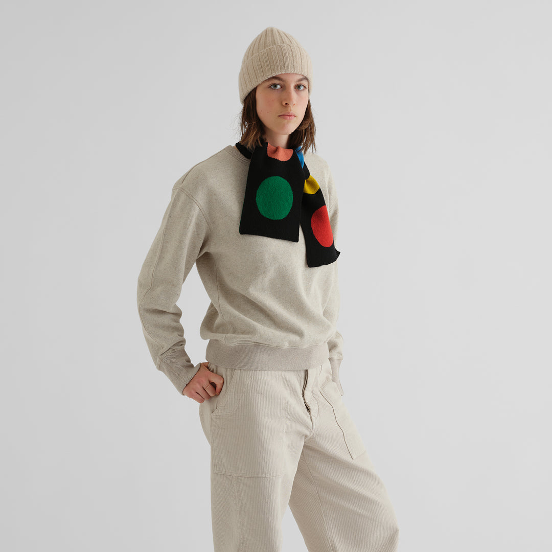 Beige sweater and black scarf with colorful circles.