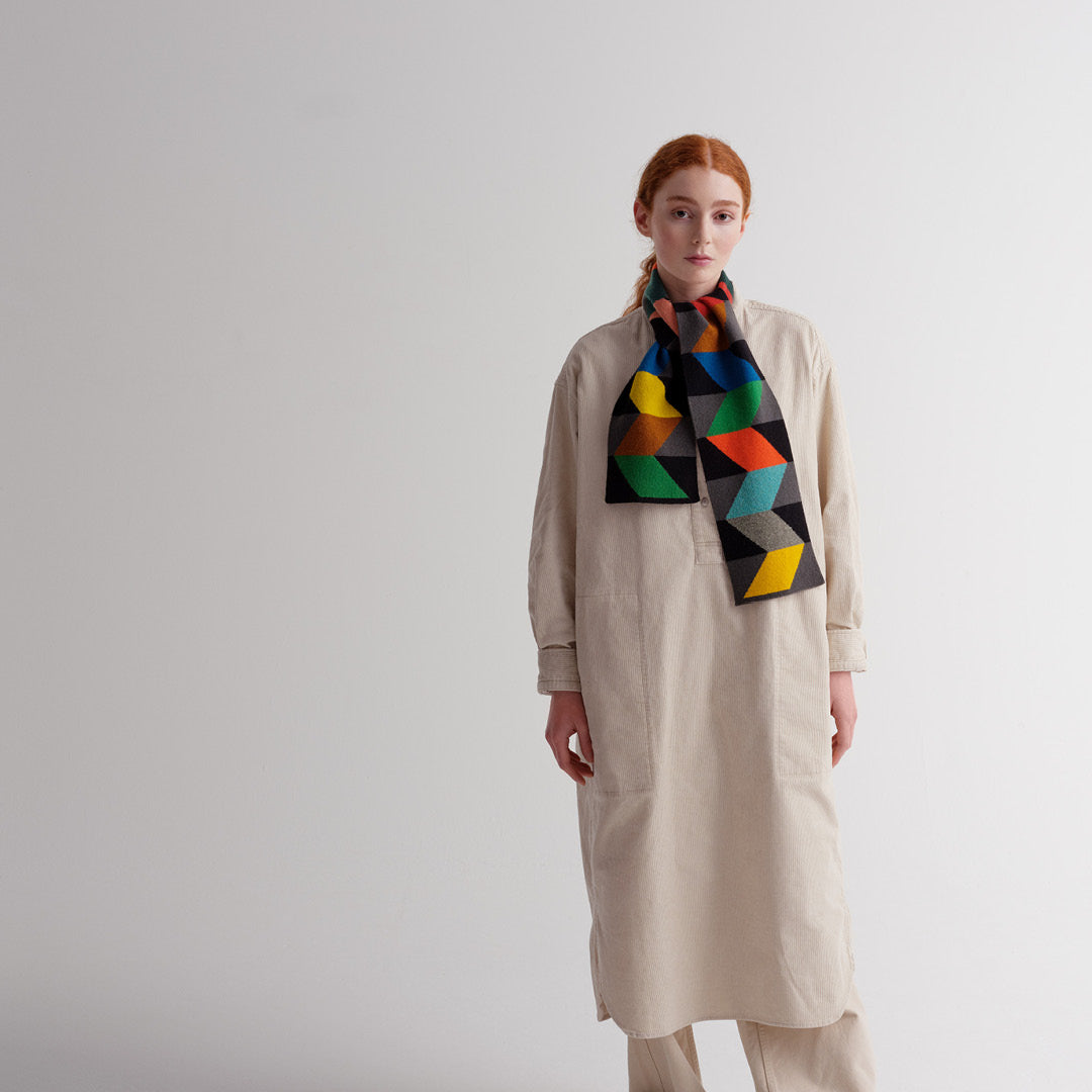Beige corduroy shirt dress with a multicolored geometric patterned scarf.