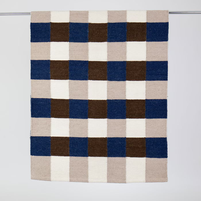 Checkered blanket with blue, brown, and beige squares on a white background