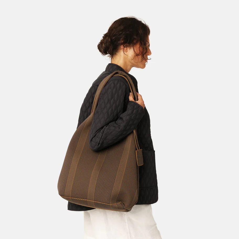Woman carrying a brown tote bag on a white background