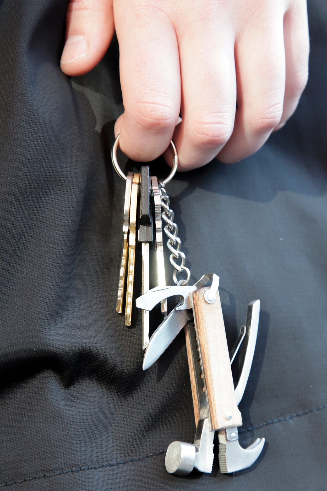 Multi-tool keychain with hammer, knife, and other tools attached to several keys on a ring.