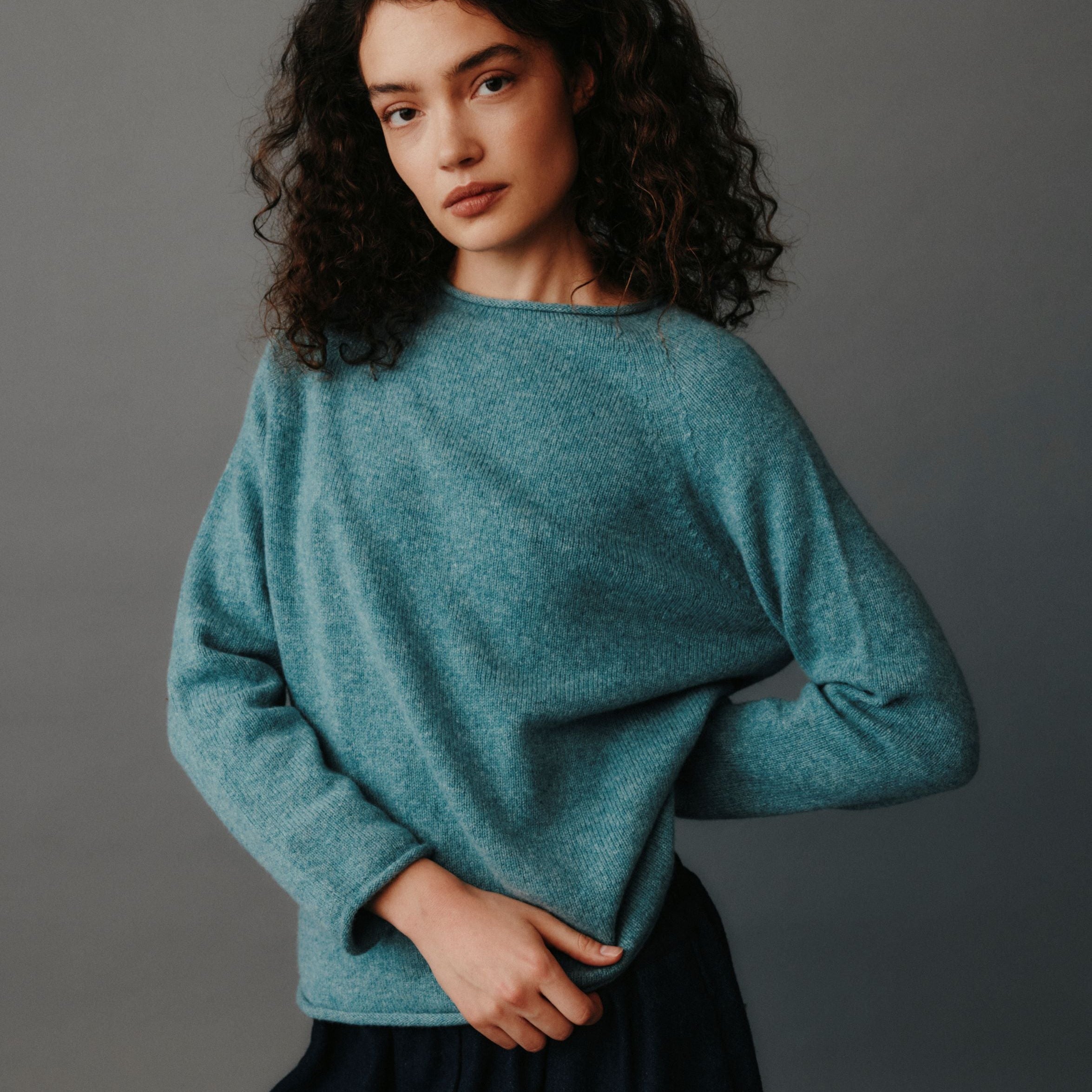 Woman wearing a teal sweater against a gray background