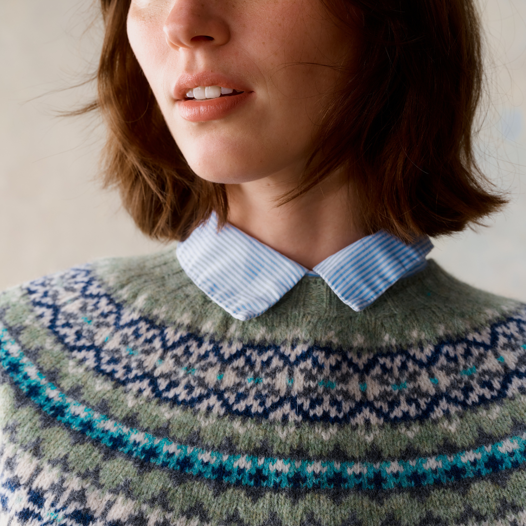 Fair isle knit sweater in sage green with teal, blue, and gray patterned yoke.