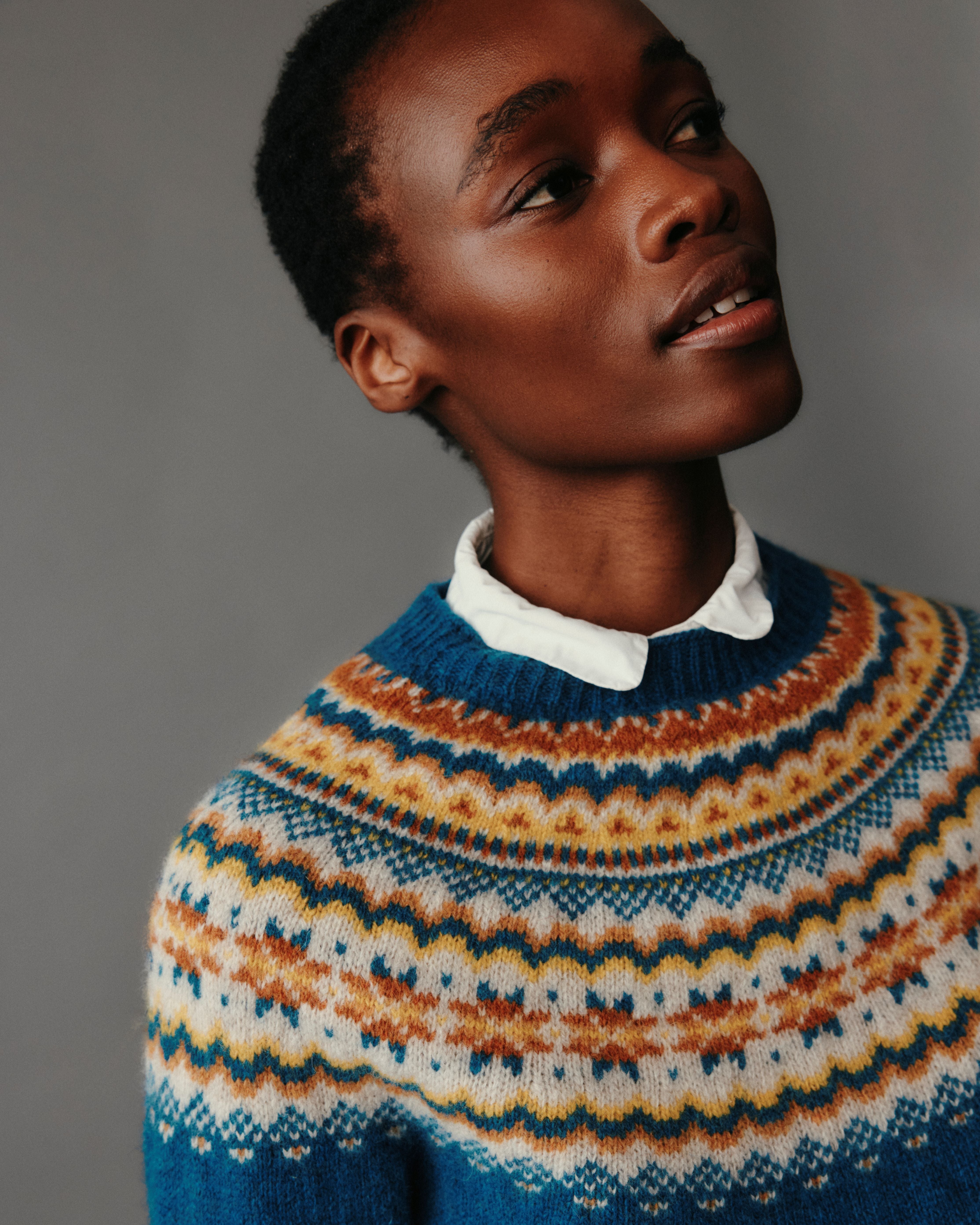 Person wearing a blue and orange patterned sweater against a gray background