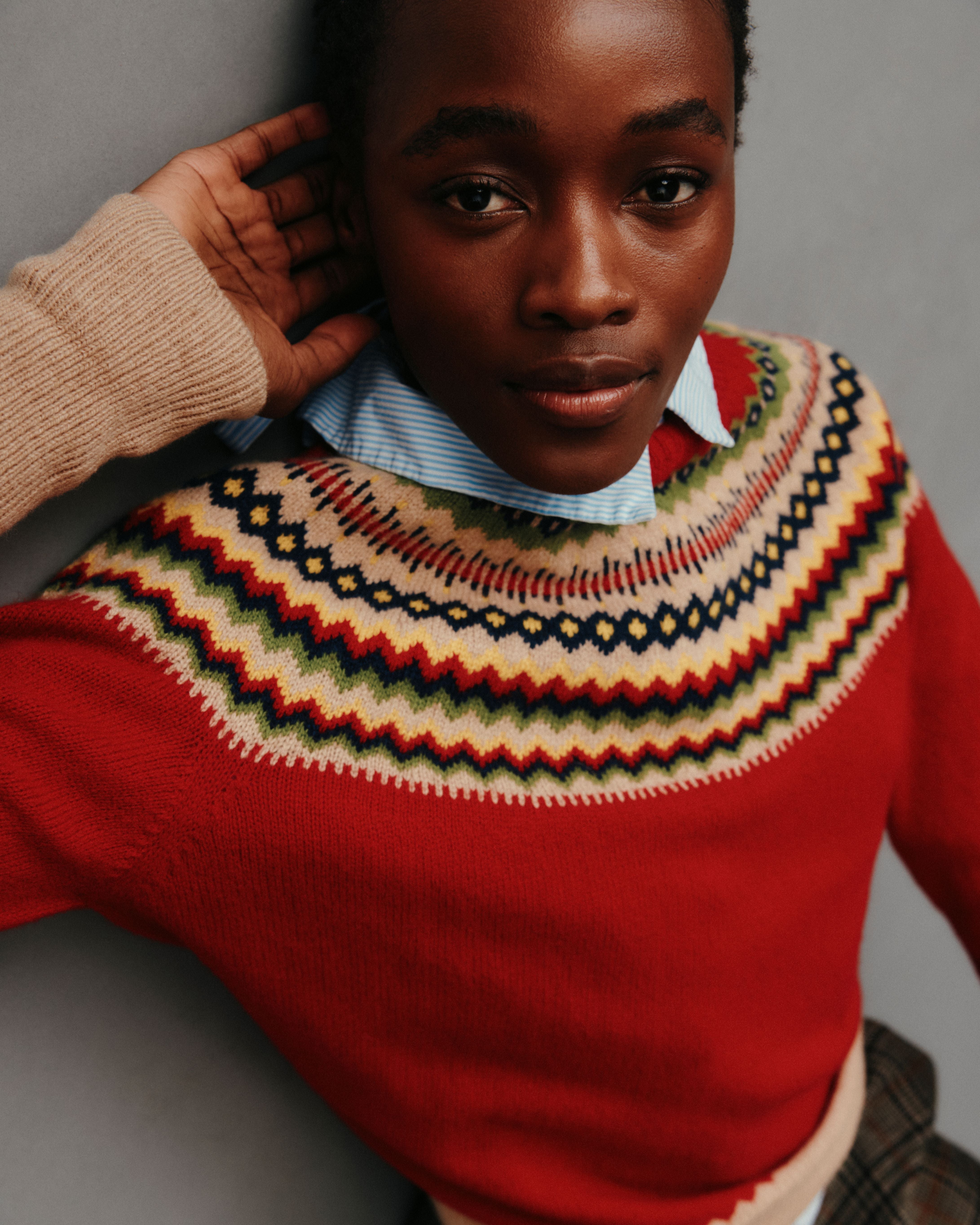 Person wearing a red sweater with a patterned collar against a neutral background