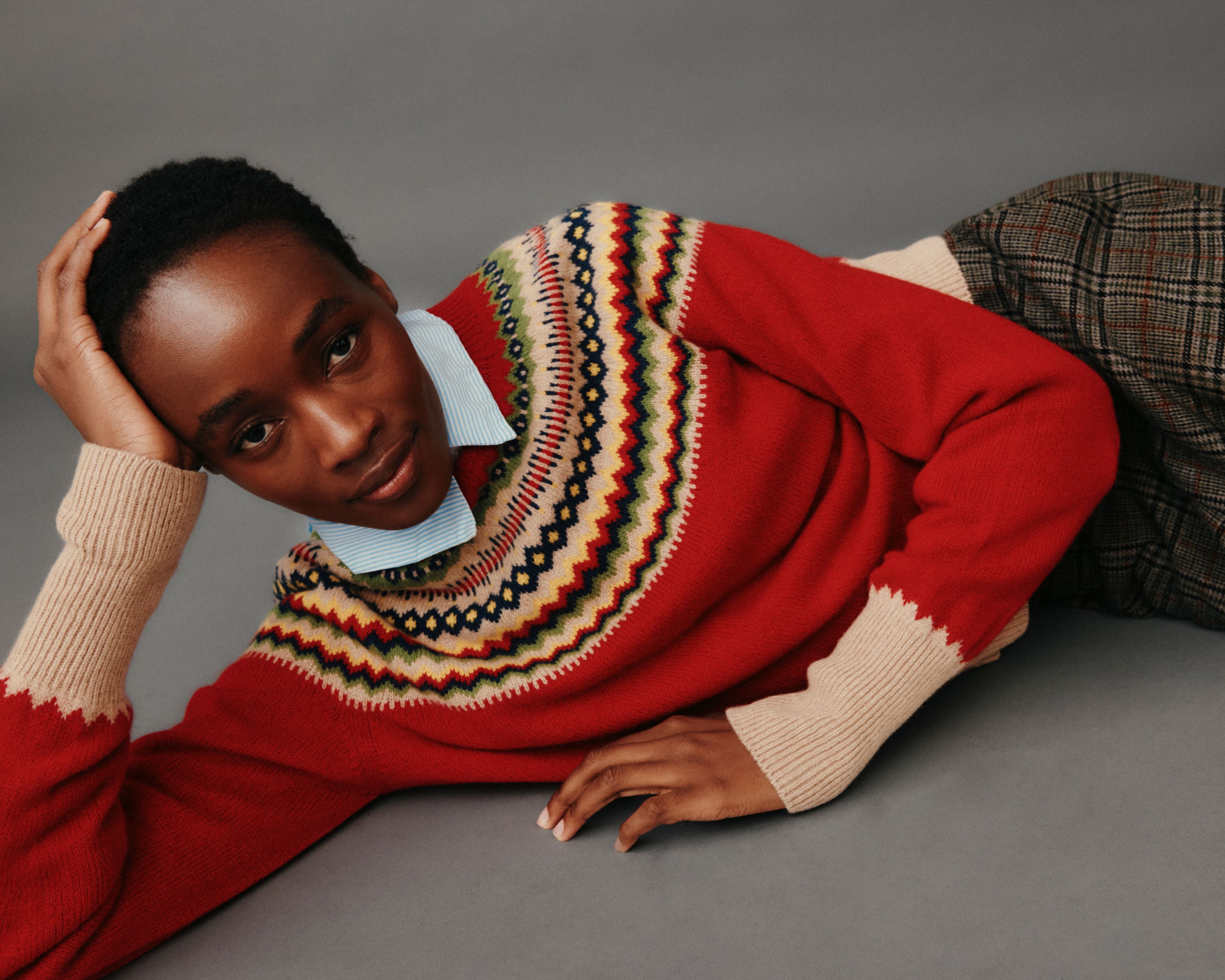 Person wearing a red sweater with a patterned neckline against a gray background