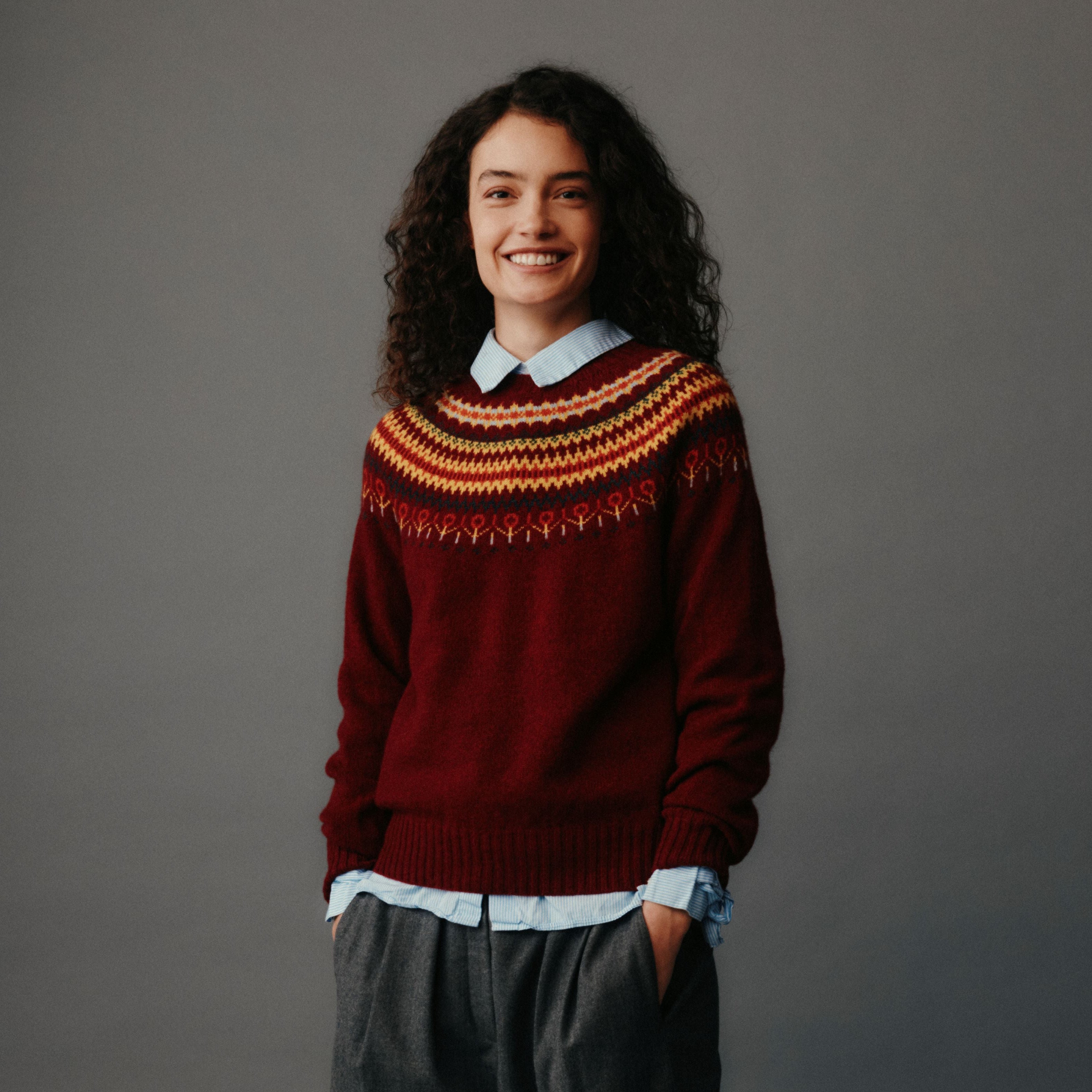 Person wearing a patterned sweater against a gray background