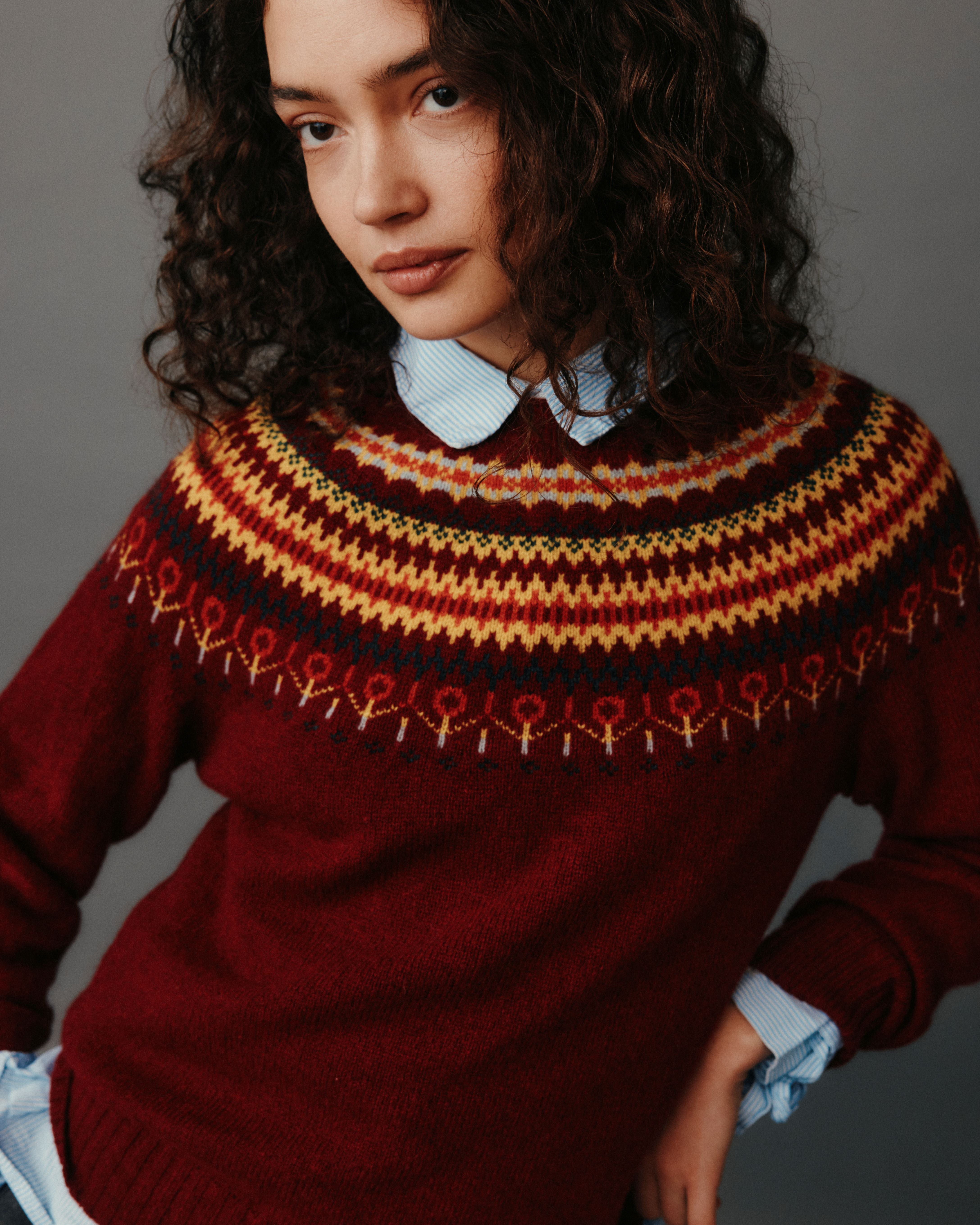 Person wearing a red sweater with a patterned collar against a gray background