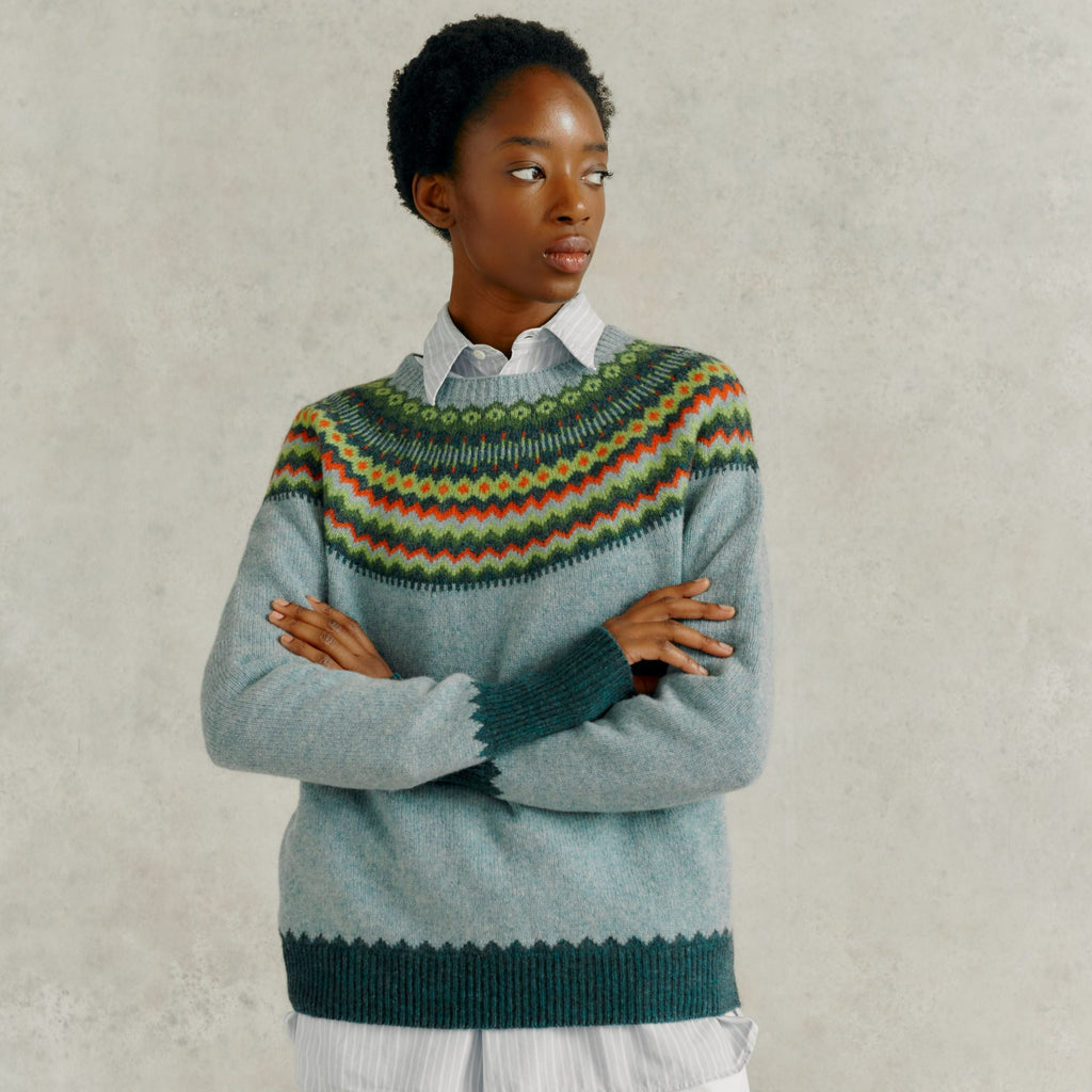 Light blue crewneck sweater with a colorful Fair Isle-style yoke and dark teal ribbed cuffs and hem.