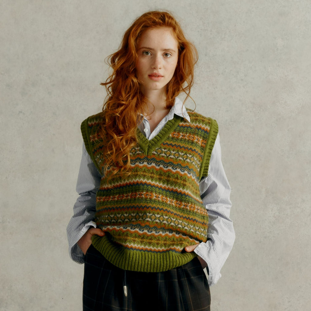 a red haired female model wearing a loose cuffed blue shirt and a Harley of Scotland Fairisle Slipover - Olive Grove
