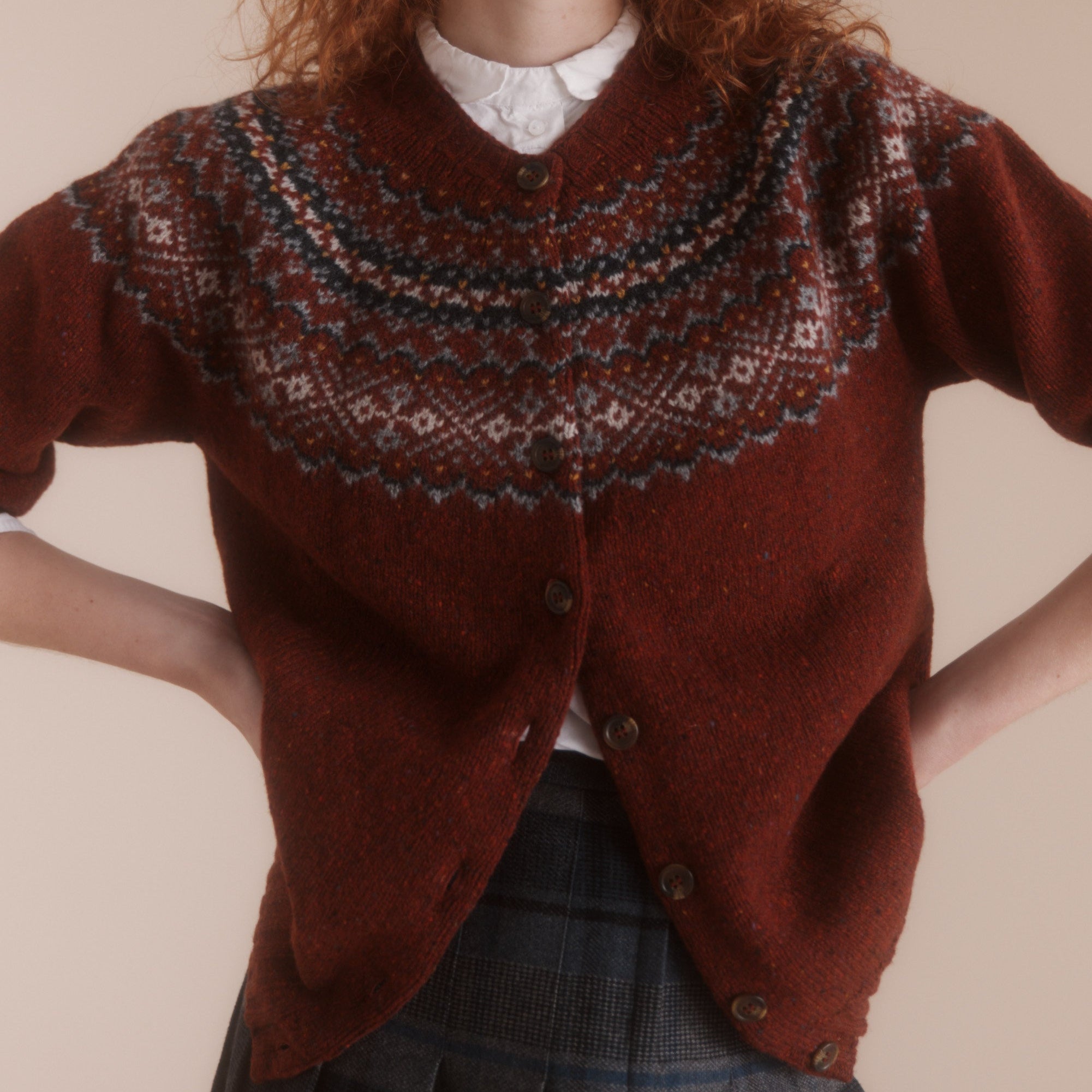 A red and blue Fairisle cardigan with buttoned front, showcasing traditional Scottish knitting patterns.