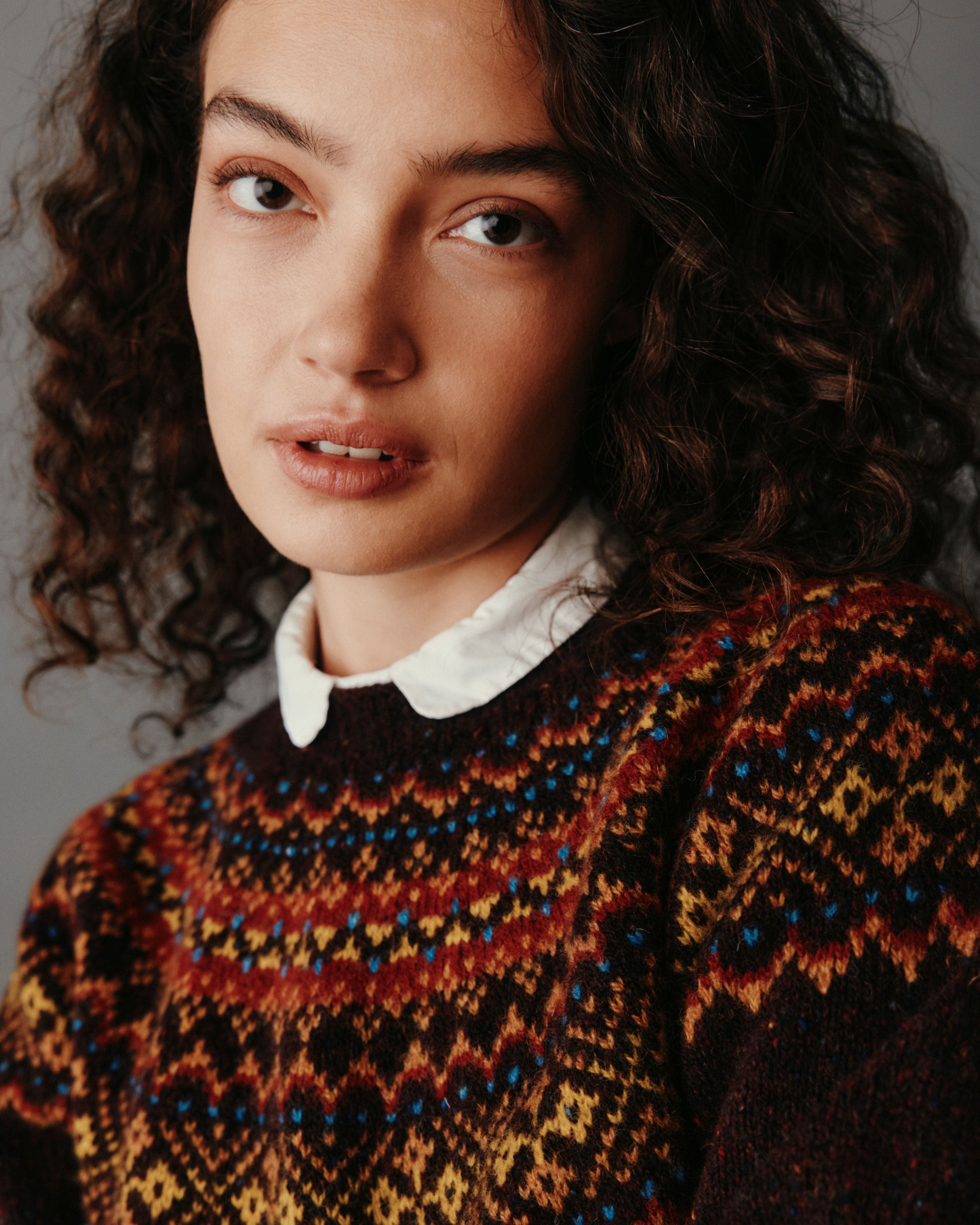 Woman wearing a patterned sweater against a neutral background