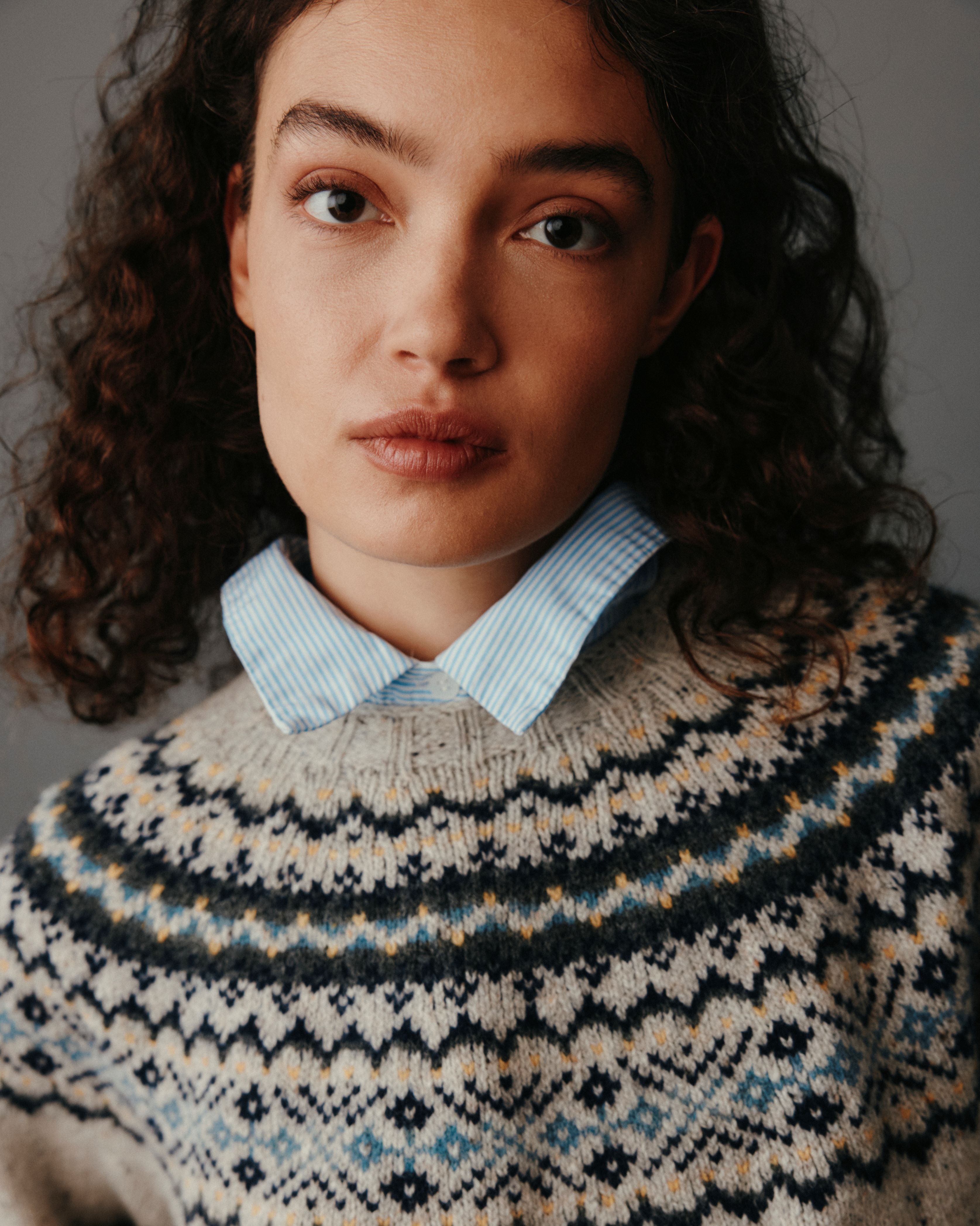 Person wearing a patterned sweater with a plain background