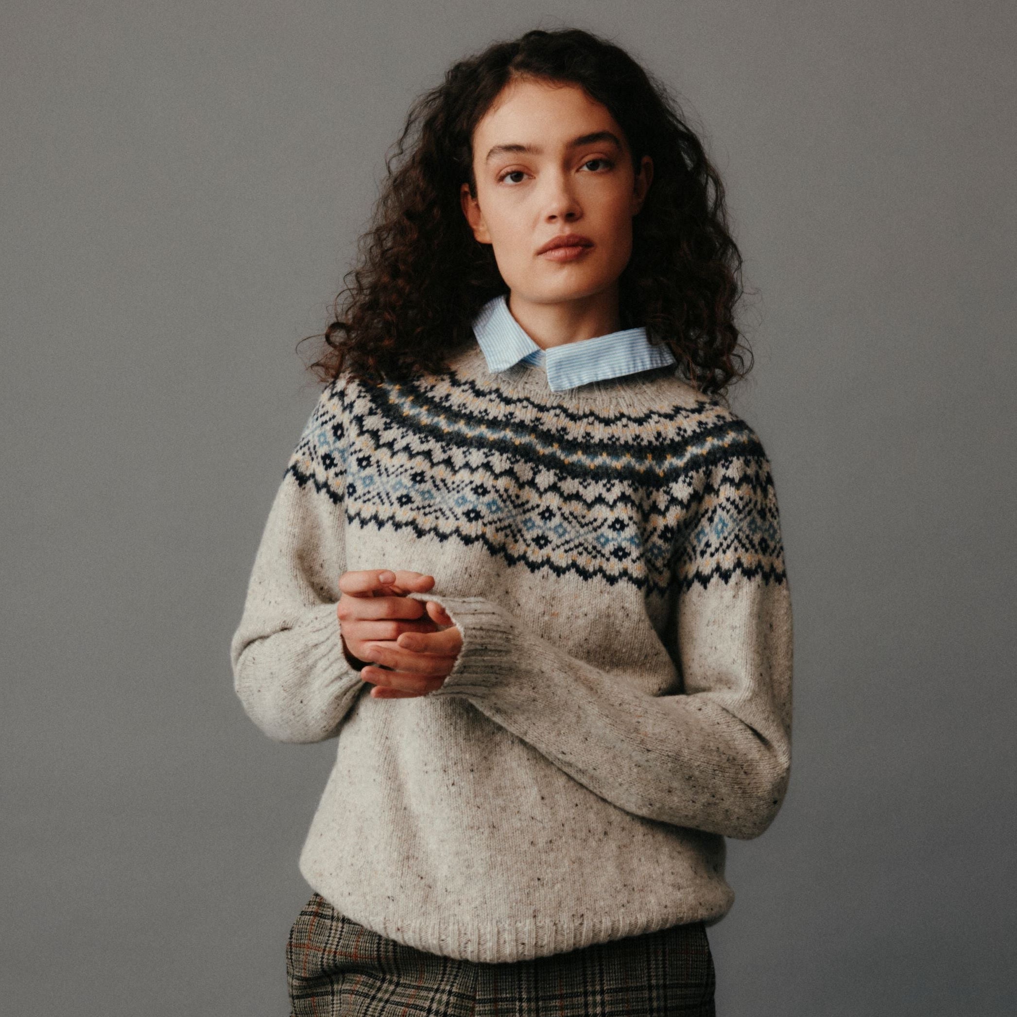 Woman wearing a patterned sweater against a gray background