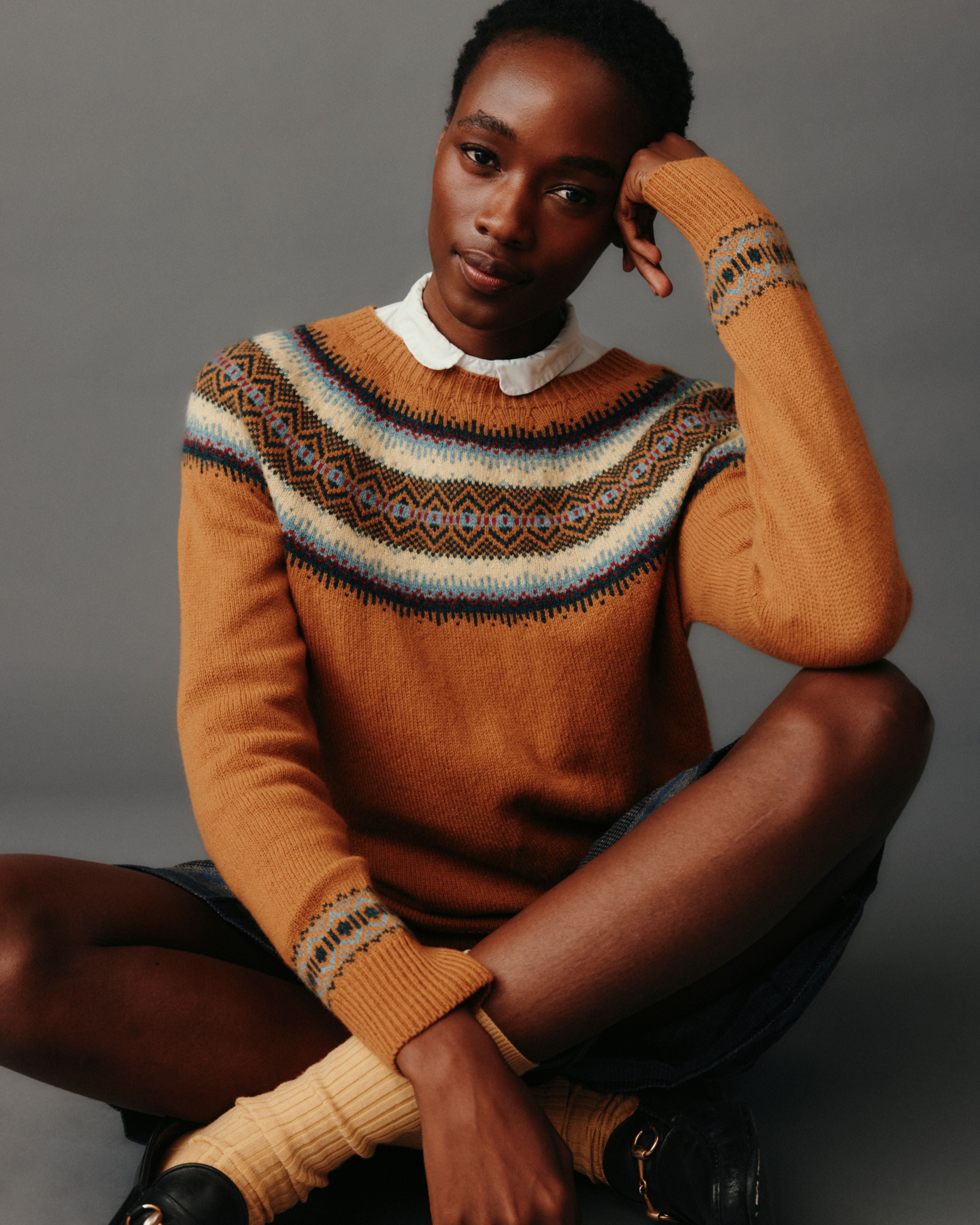 Woman wearing a patterned brown sweater against a gray background