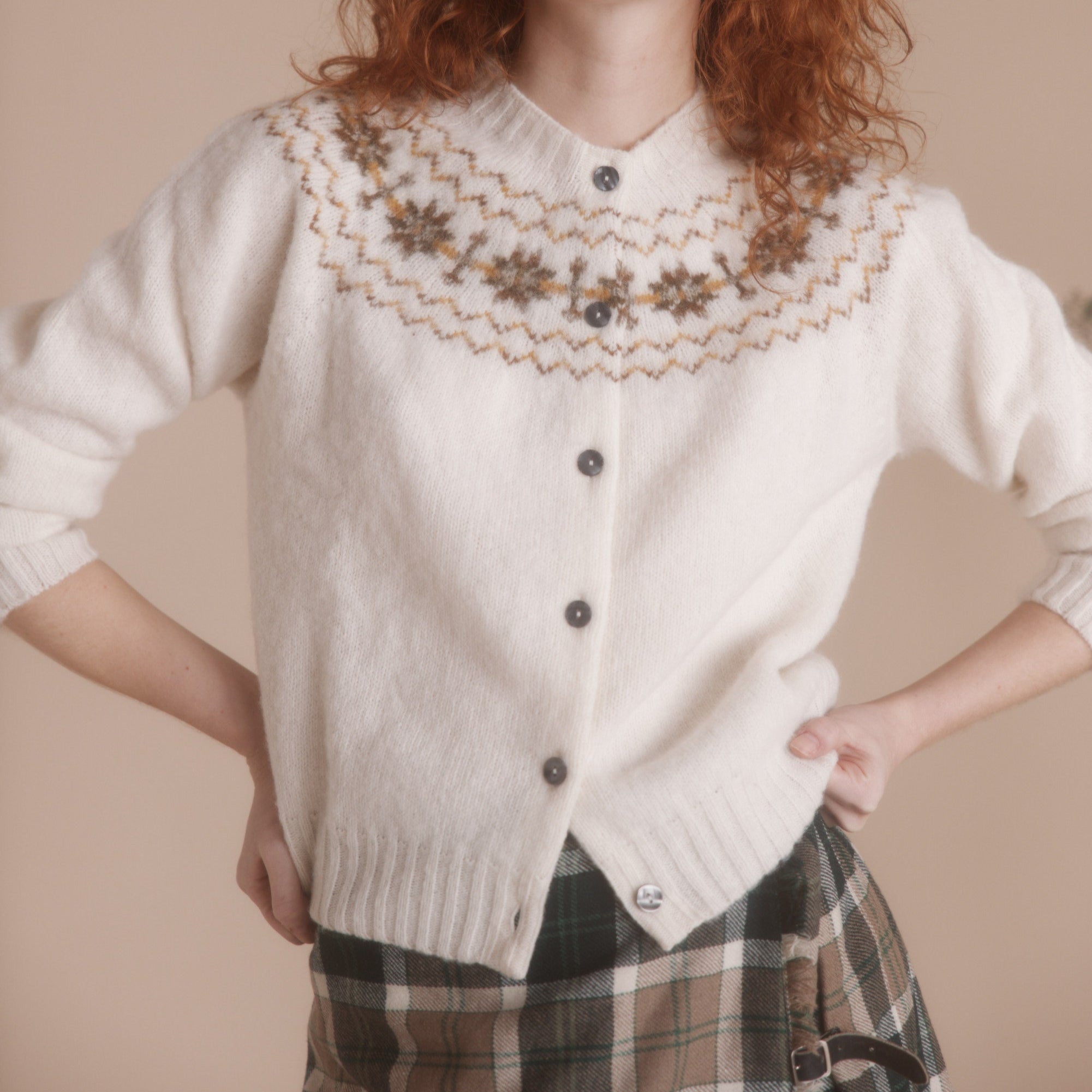 Cream-colored fuzzy cardigan sweater with a brown and beige Fair Isle yoke pattern and dark buttons.