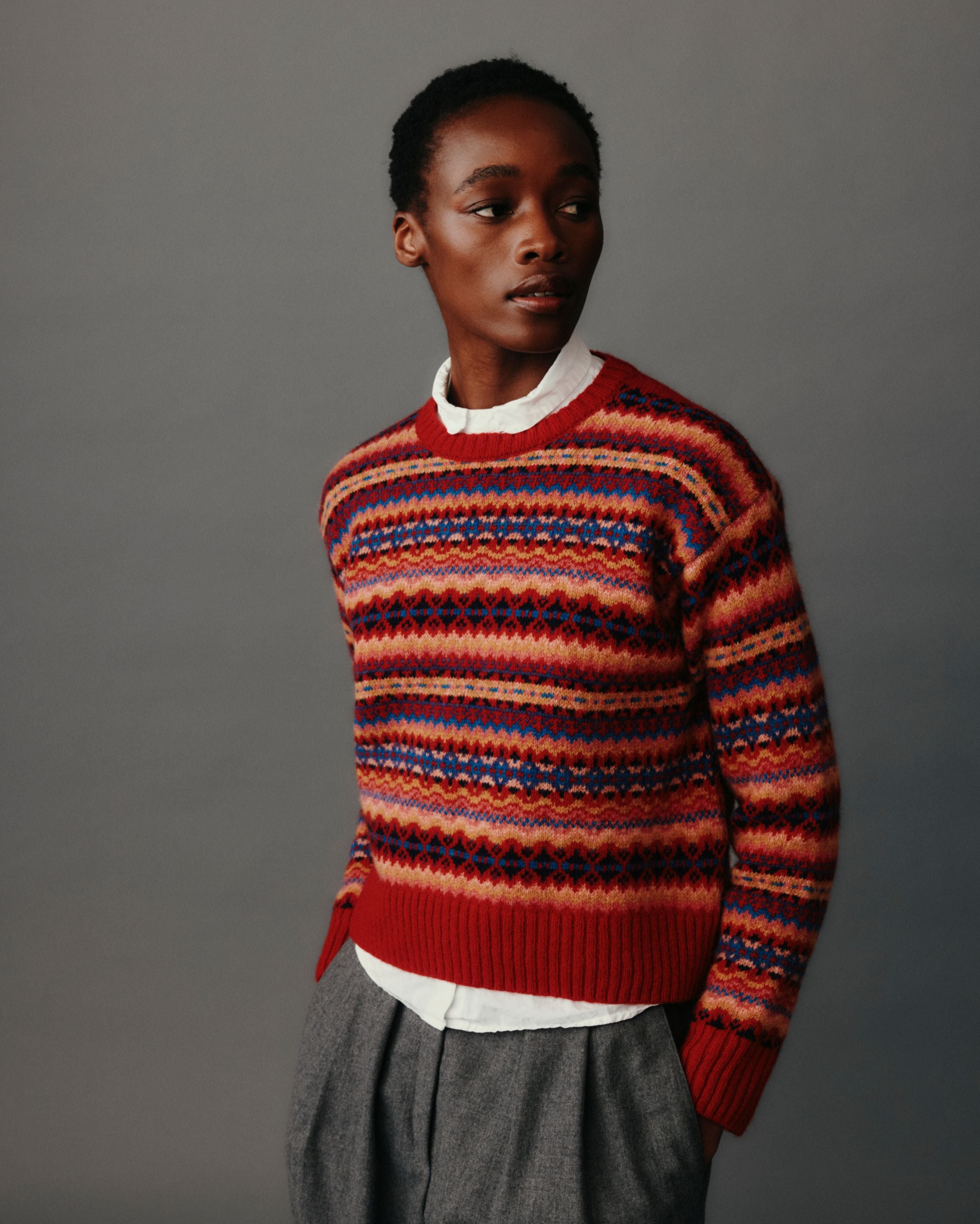 Person wearing a colorful striped sweater against a gray background